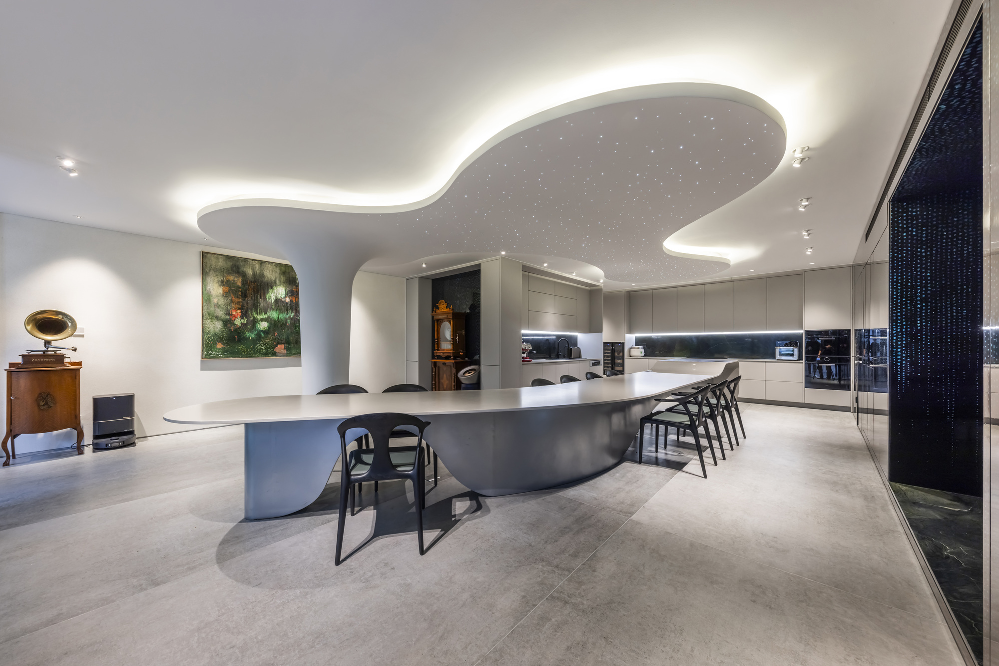 Open-plan kitchen with curved island, organic ceiling feature, and concealed uplighting
