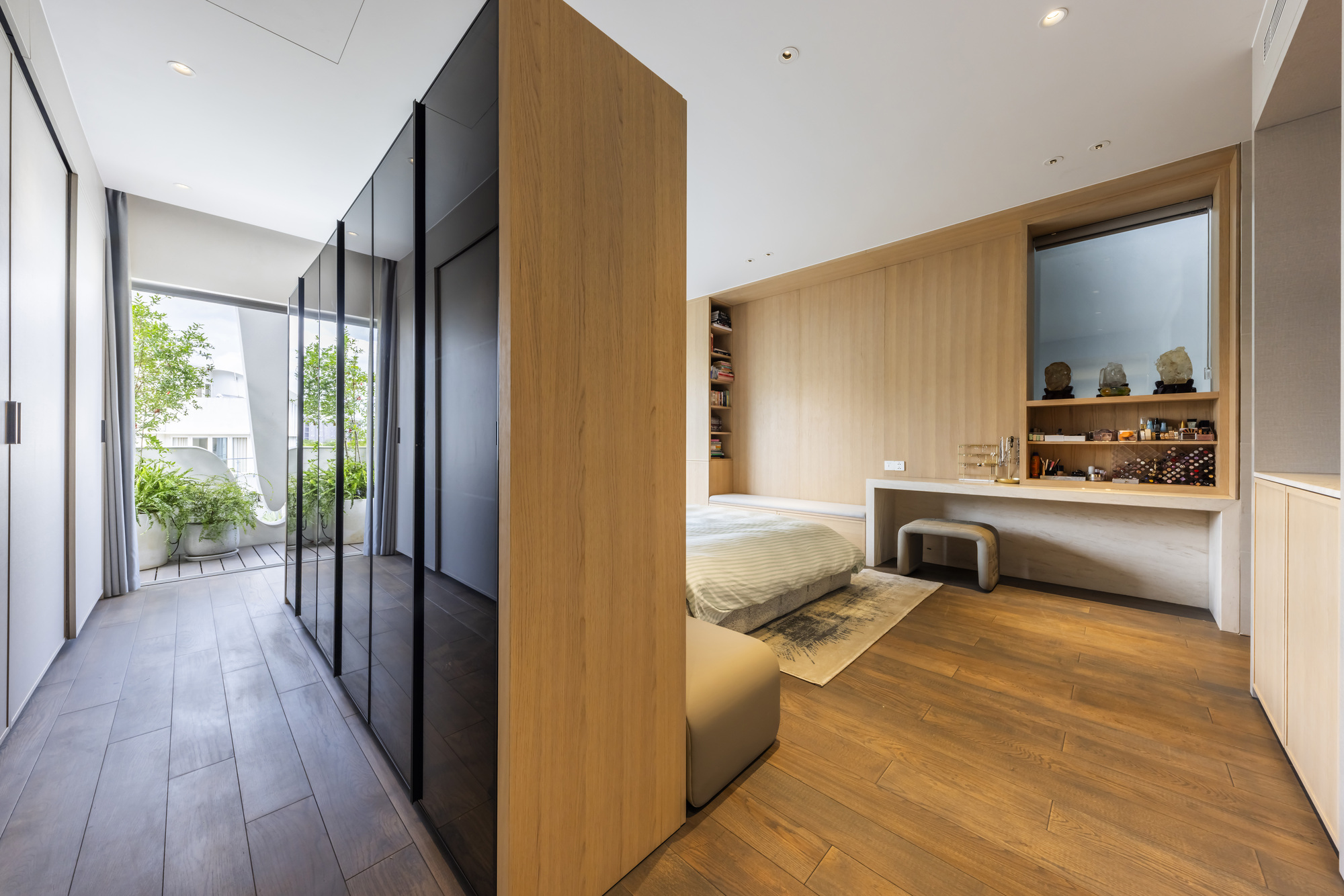 Bedroom with timber-clad partition and dark wardrobes opening to a planted terrace