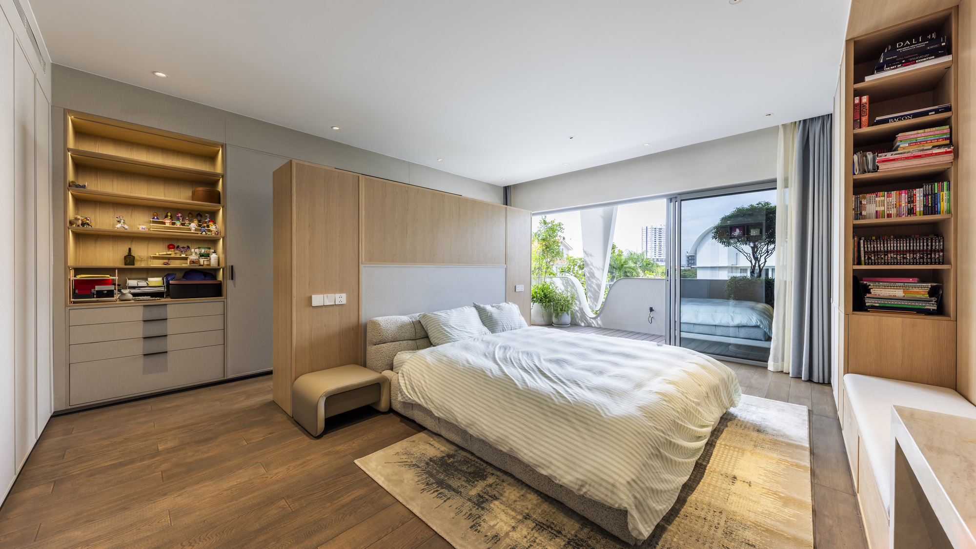 Bedroom with light wood millwork and built-in shelving framing a sliding glass door to a balcony