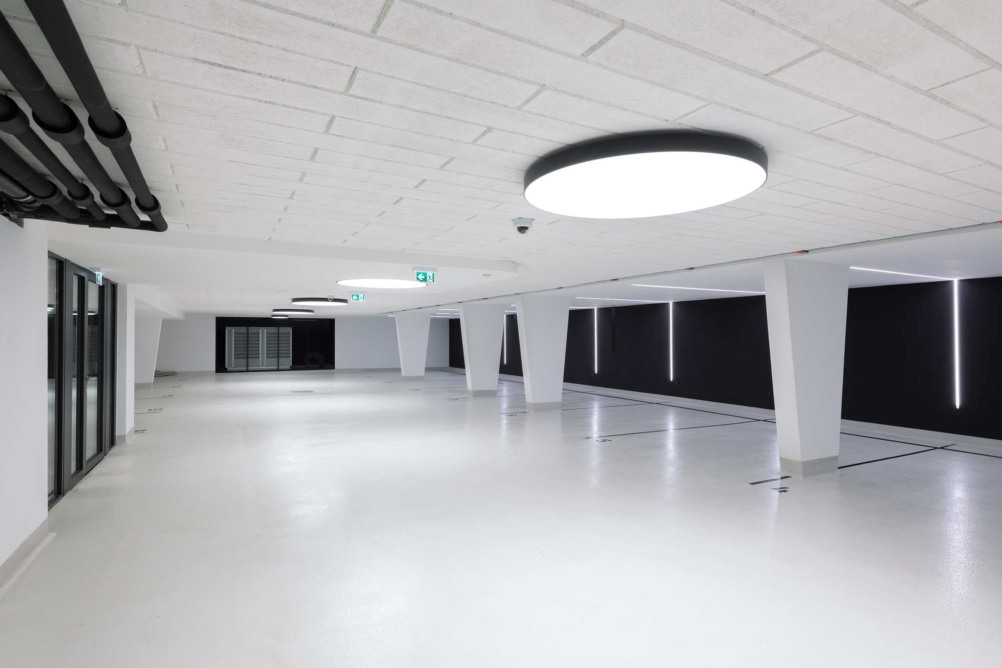 Underground parking garage with white epoxy floor, angled columns, and black recessed lighting panels