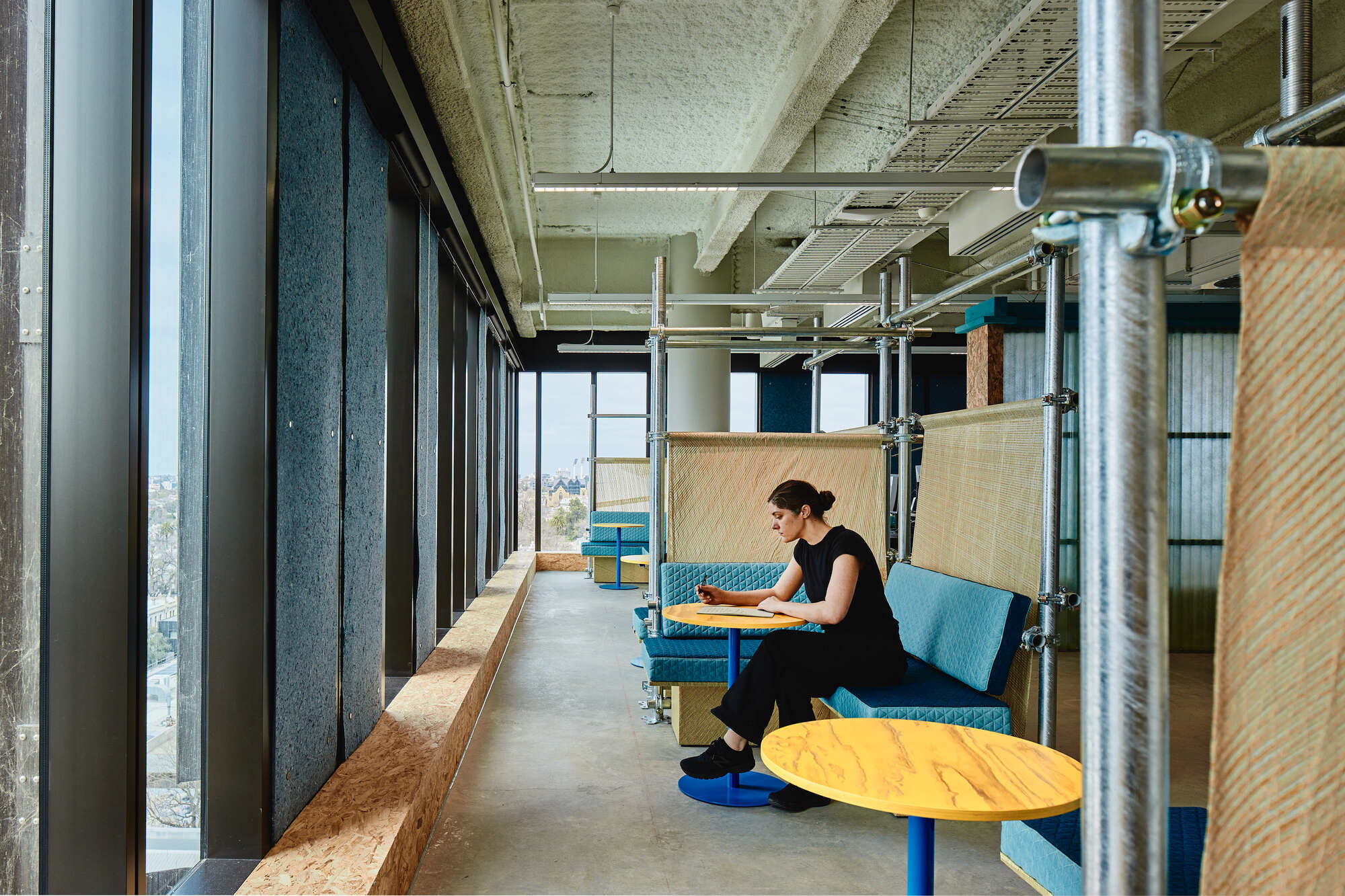 Window counter with built-in seating and a person working at low table with yellow top