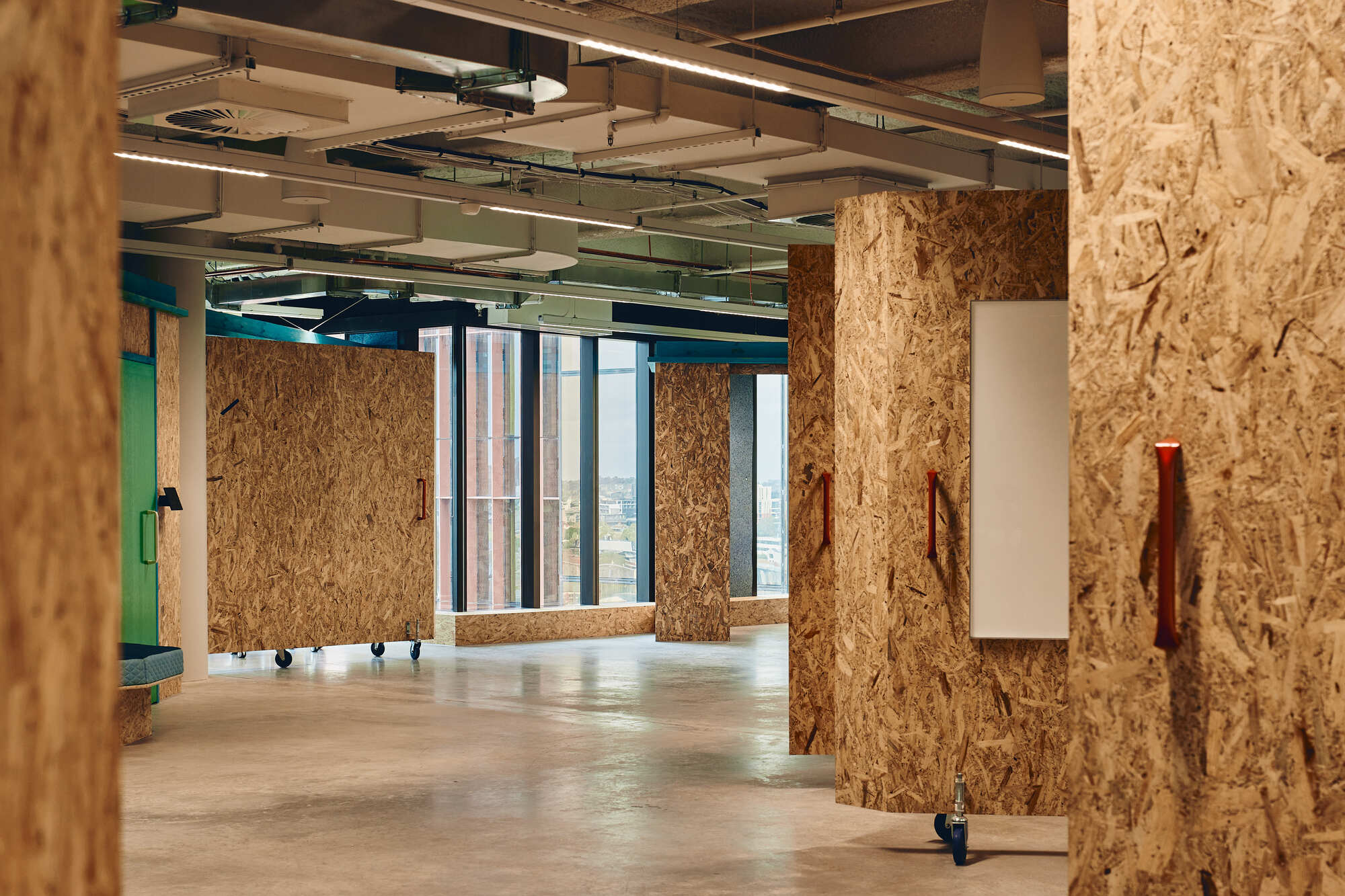 Open floor with oriented strand board columns, movable partition panels on casters, and polished concrete flooring