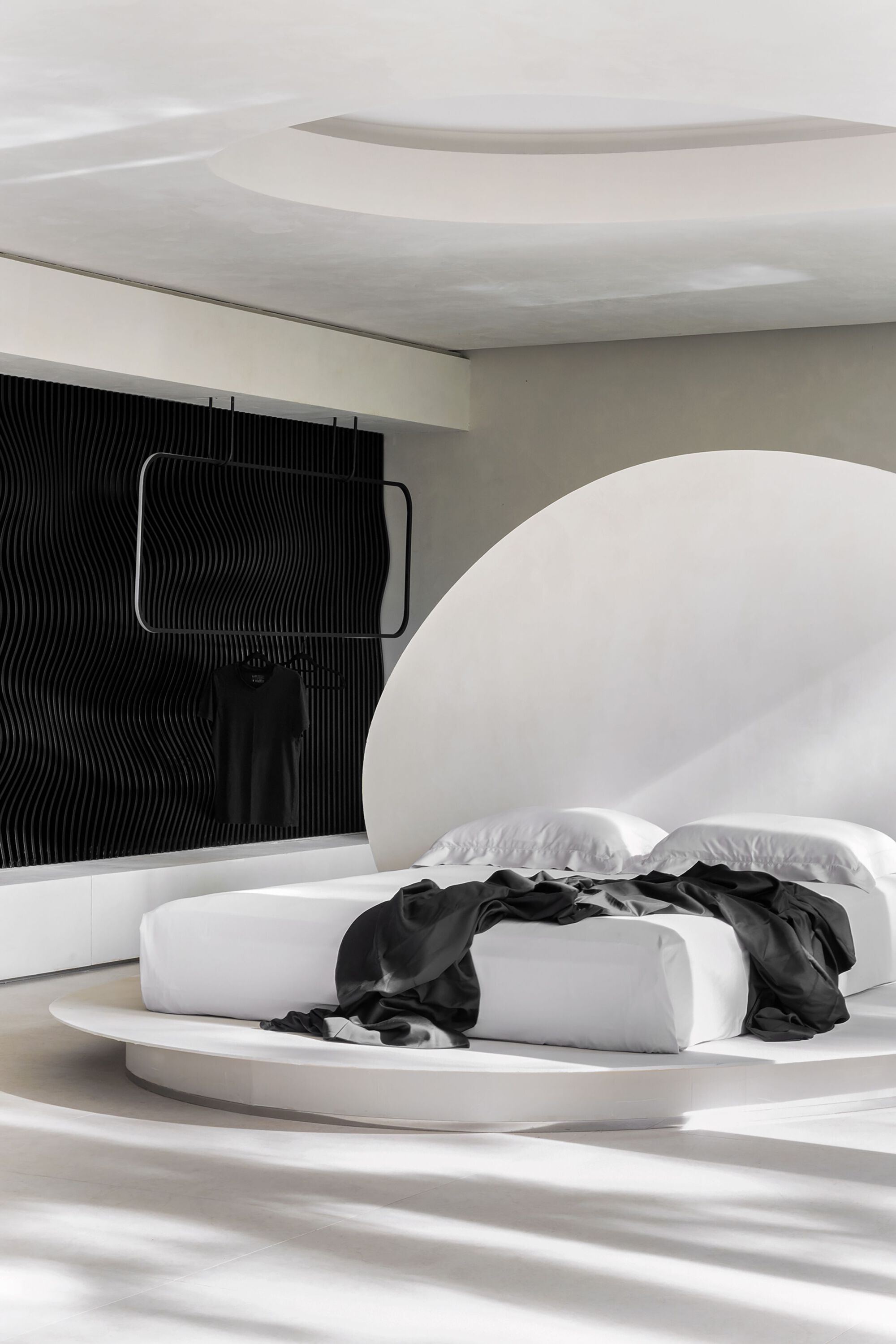 Oblique view of the rounded headboard niche and ribbed black accent wall in soft daylight