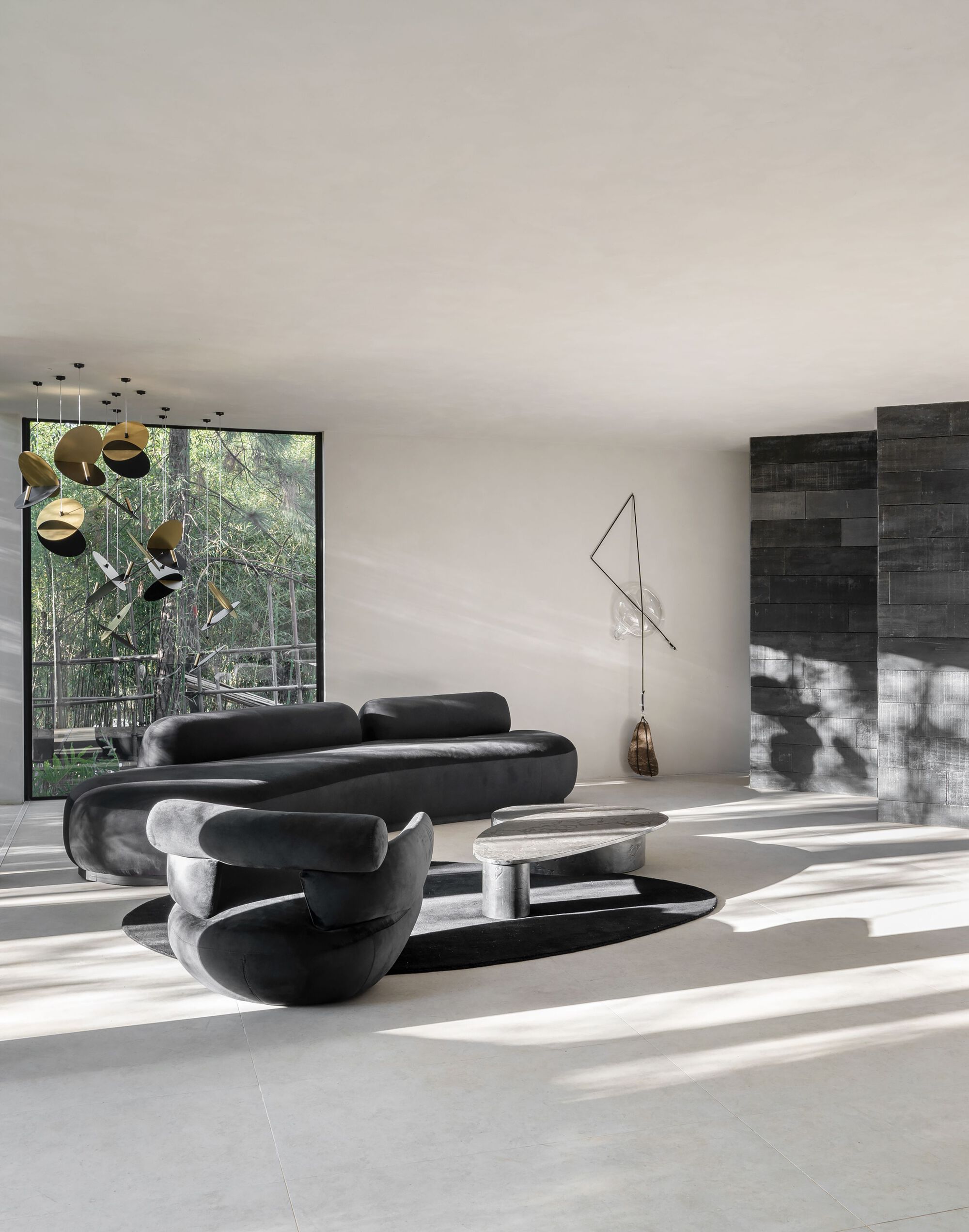 Living area with sculptural seating beneath recessed ceiling lights and view to charred timber courtyard wall
