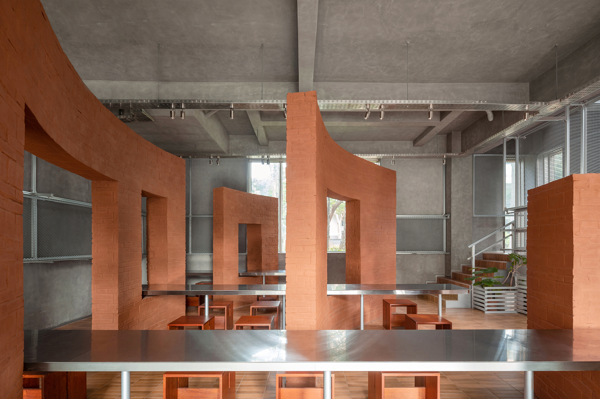 Interior with terracotta brick partitions and built-in seating beneath an exposed concrete waffle slab ceiling