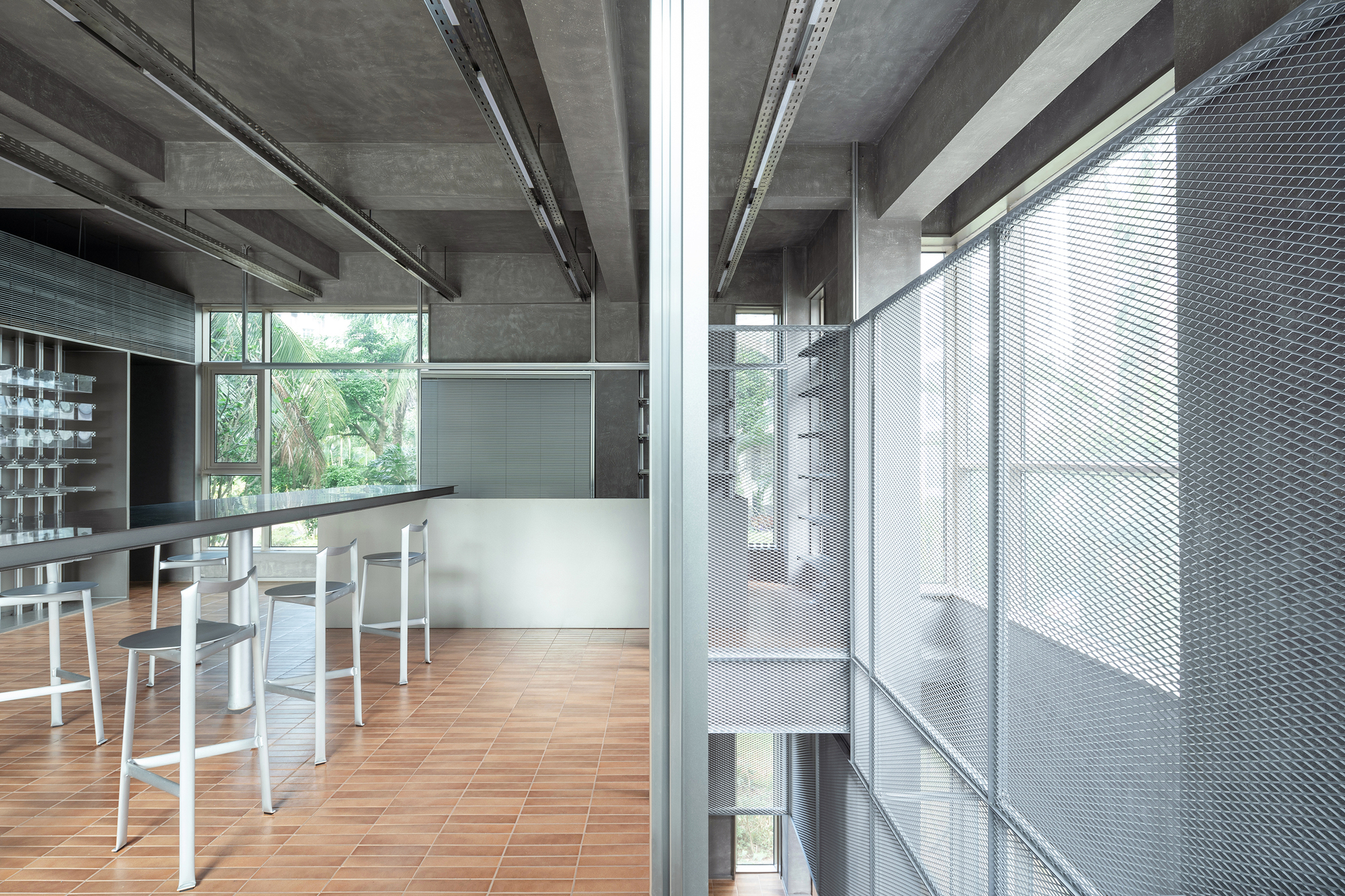 Upper-level workspace with perforated metal stair enclosure and exposed concrete ceiling structure
