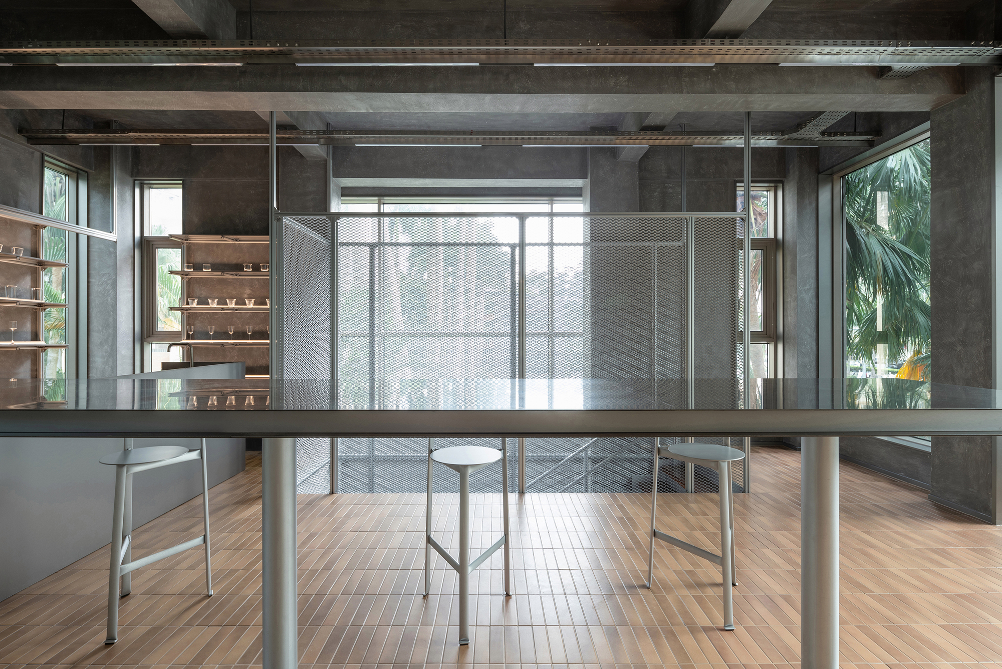 Open workspace with timber flooring and perforated metal screens dividing the exposed concrete interior