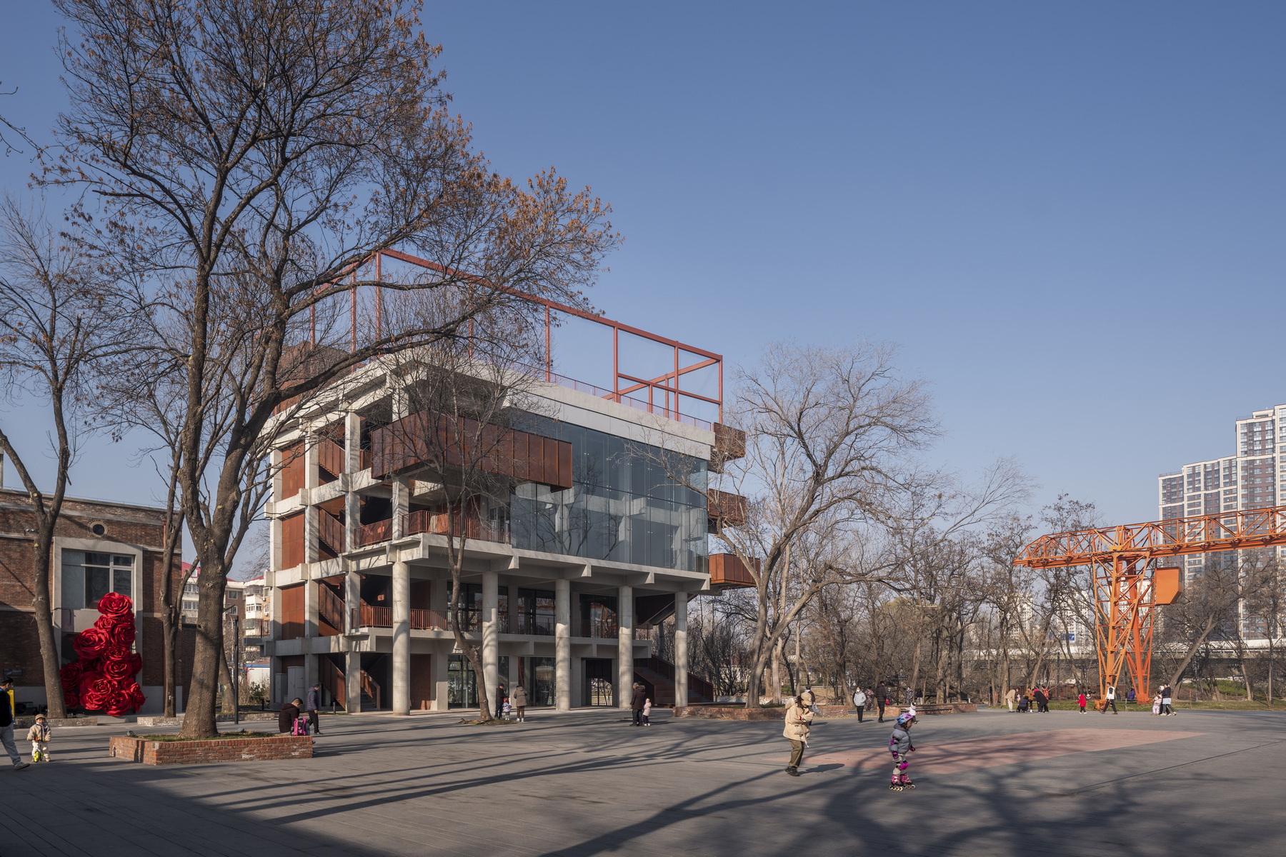 View across a plaza showing the piloti ground level and bare winter trees with children playing nearby