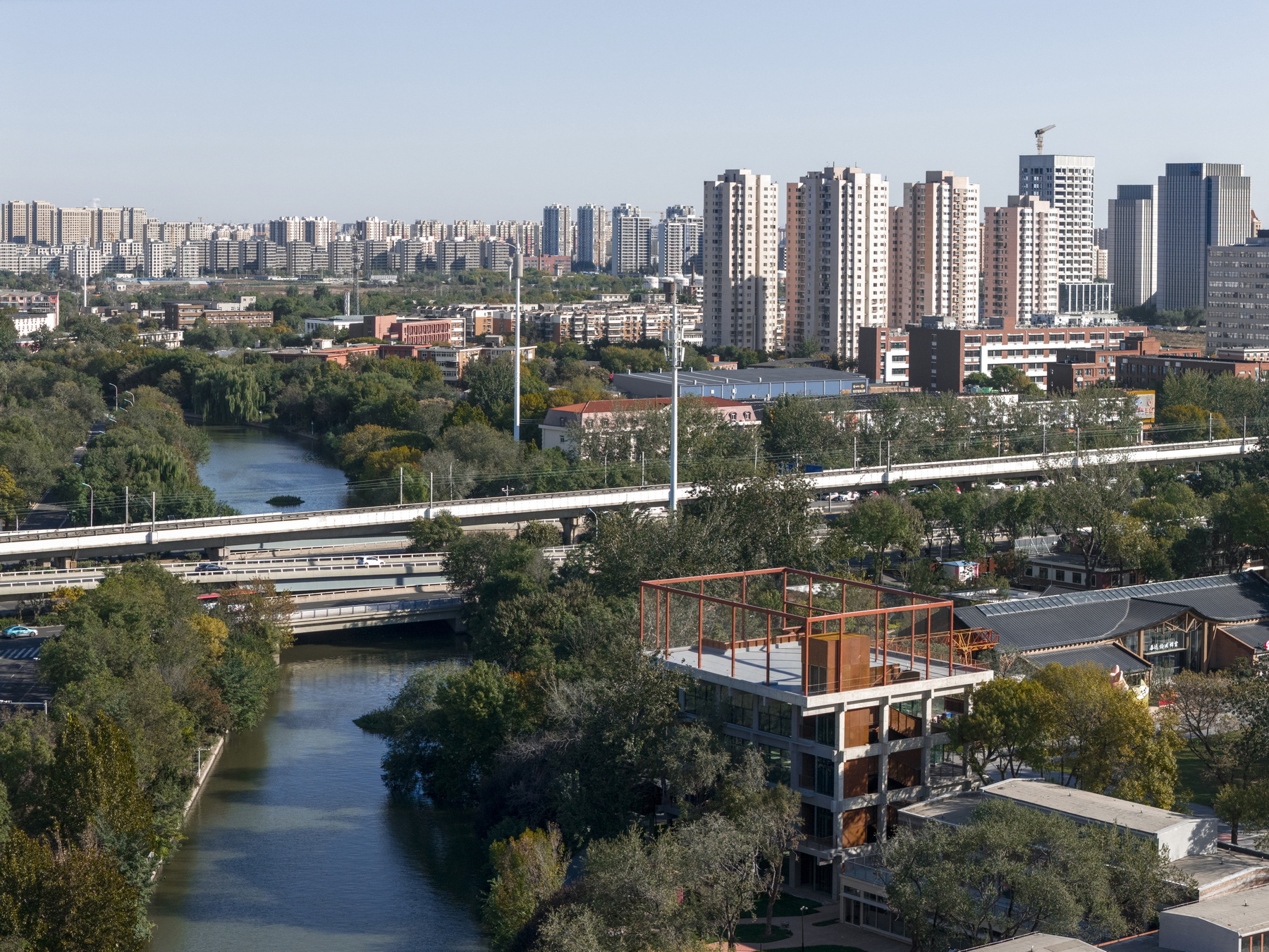 Aerial view of the rooftop steel frame above the structure with river and highway infrastructure in background
