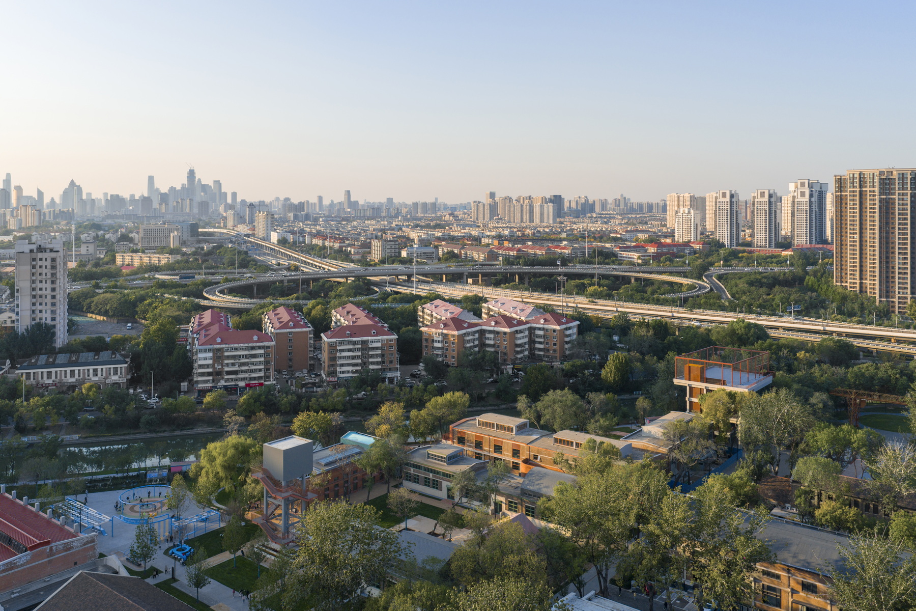 Drone view of the campus with planted grounds and surrounding residential towers at dusk