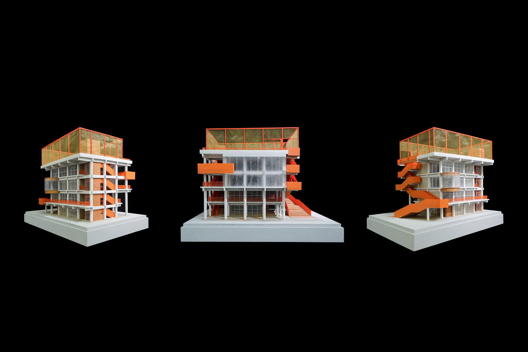 Three views of the physical model with orange external stairs wrapping the structural frame