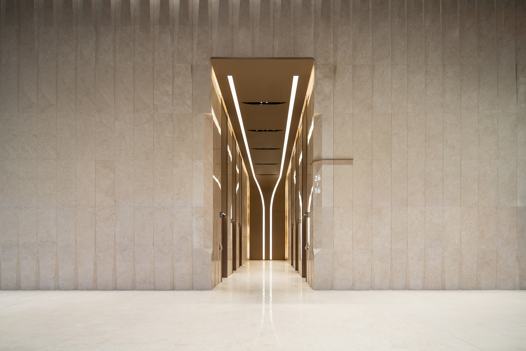 Elevator lobby framed by illuminated vertical mullions and polished stone floor reflecting overhead lighting