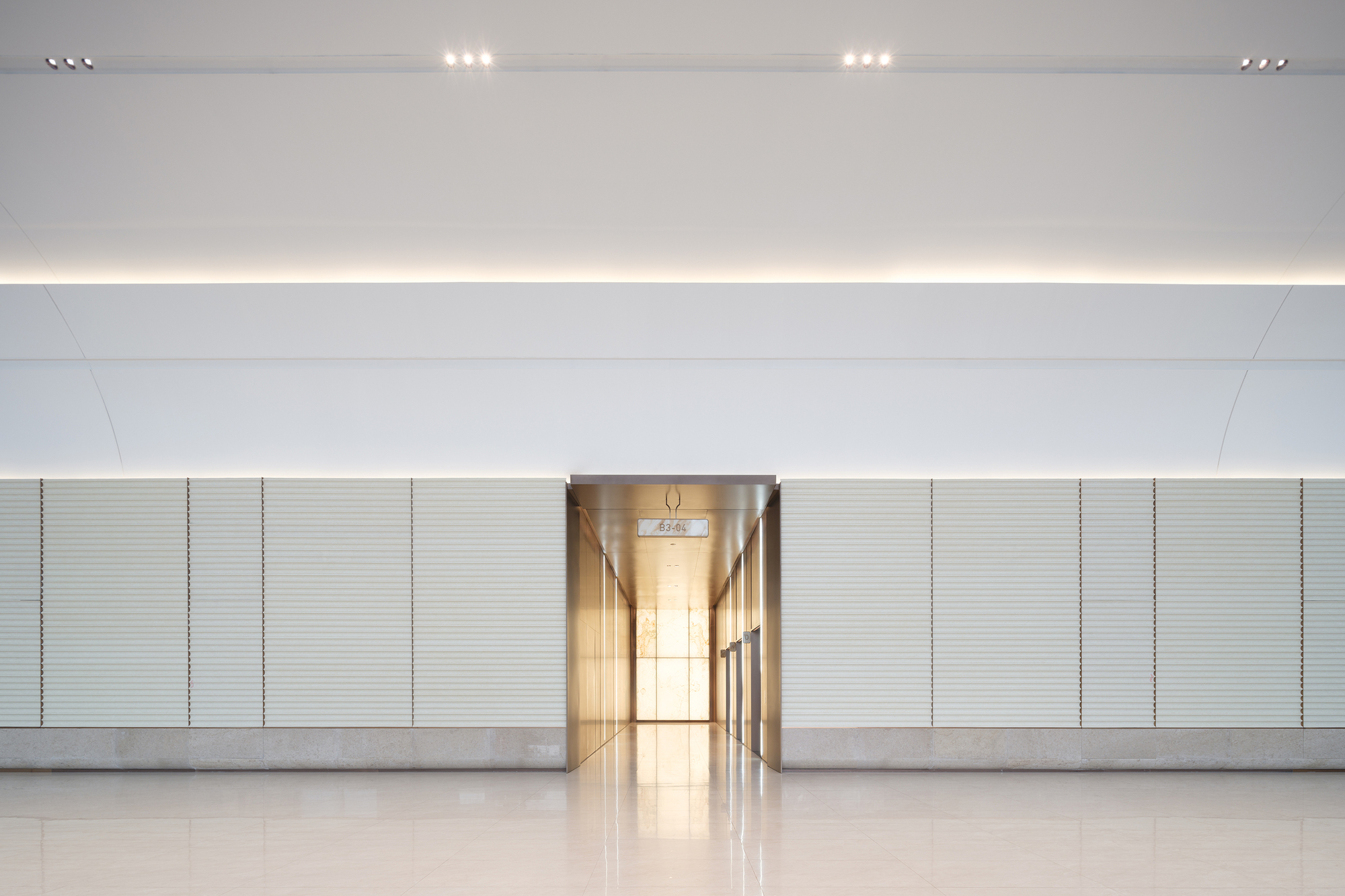Interior corridor wall with horizontal ribbed panels and illuminated central passage through the recessed lighting