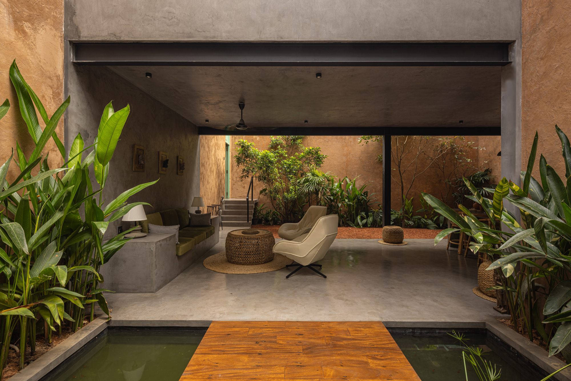 Courtyard lounge area with timber bridge crossing a narrow water feature framed by planted beds