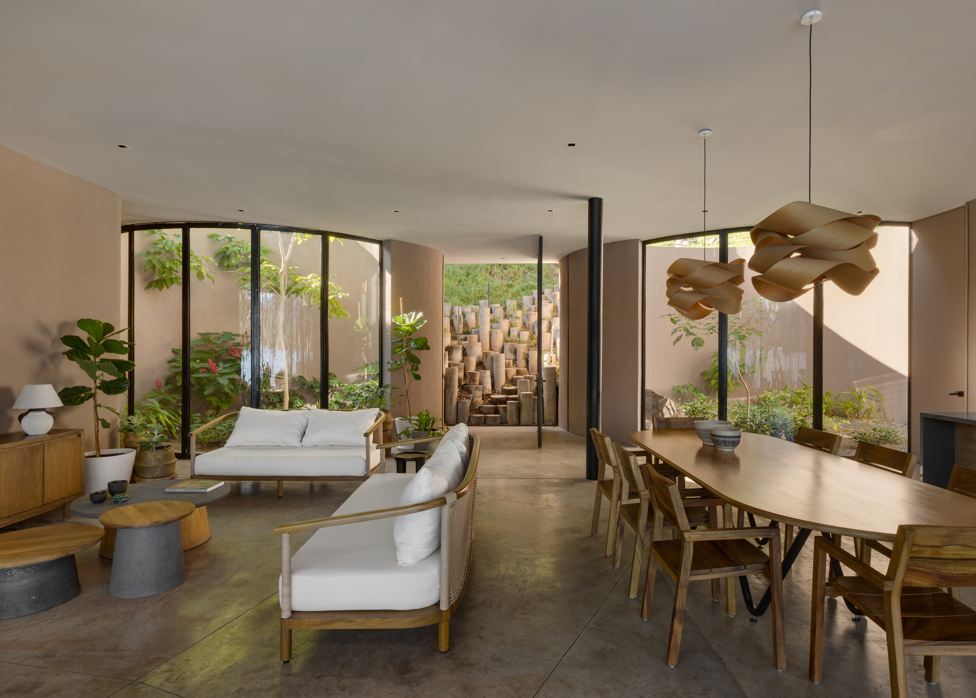 Open-plan living and dining space with floor-to-ceiling glazing overlooking a planted courtyard with textured block wall