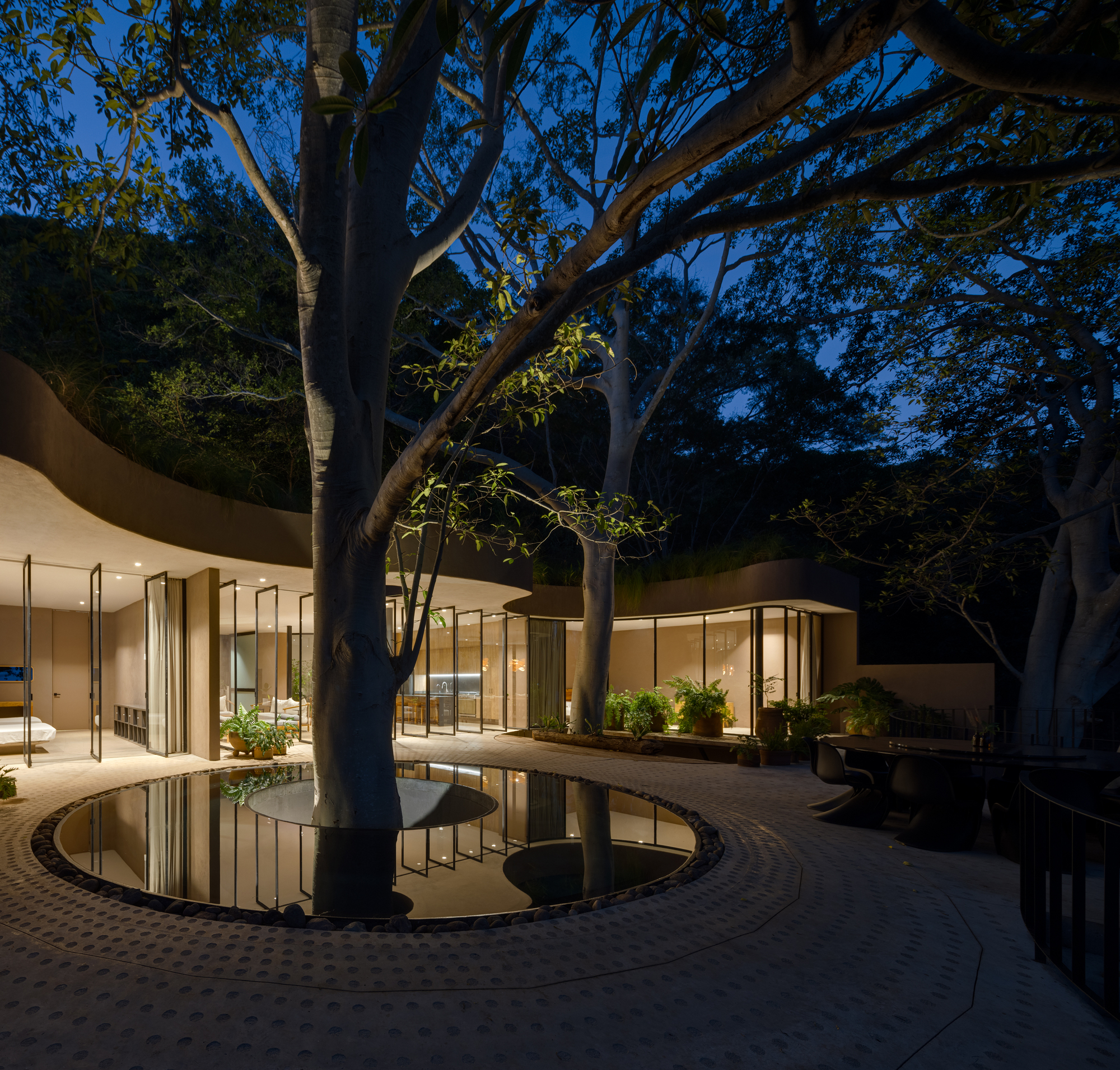 Perimeter terrace with water feature reflecting glass facades and mature trees after dark