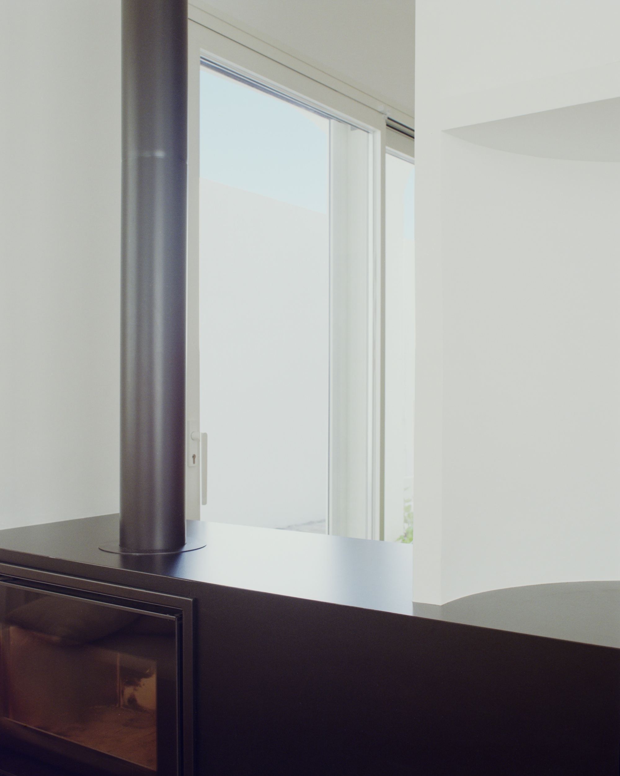 Black wood-burning stove beside sliding glass door overlooking a muted sky