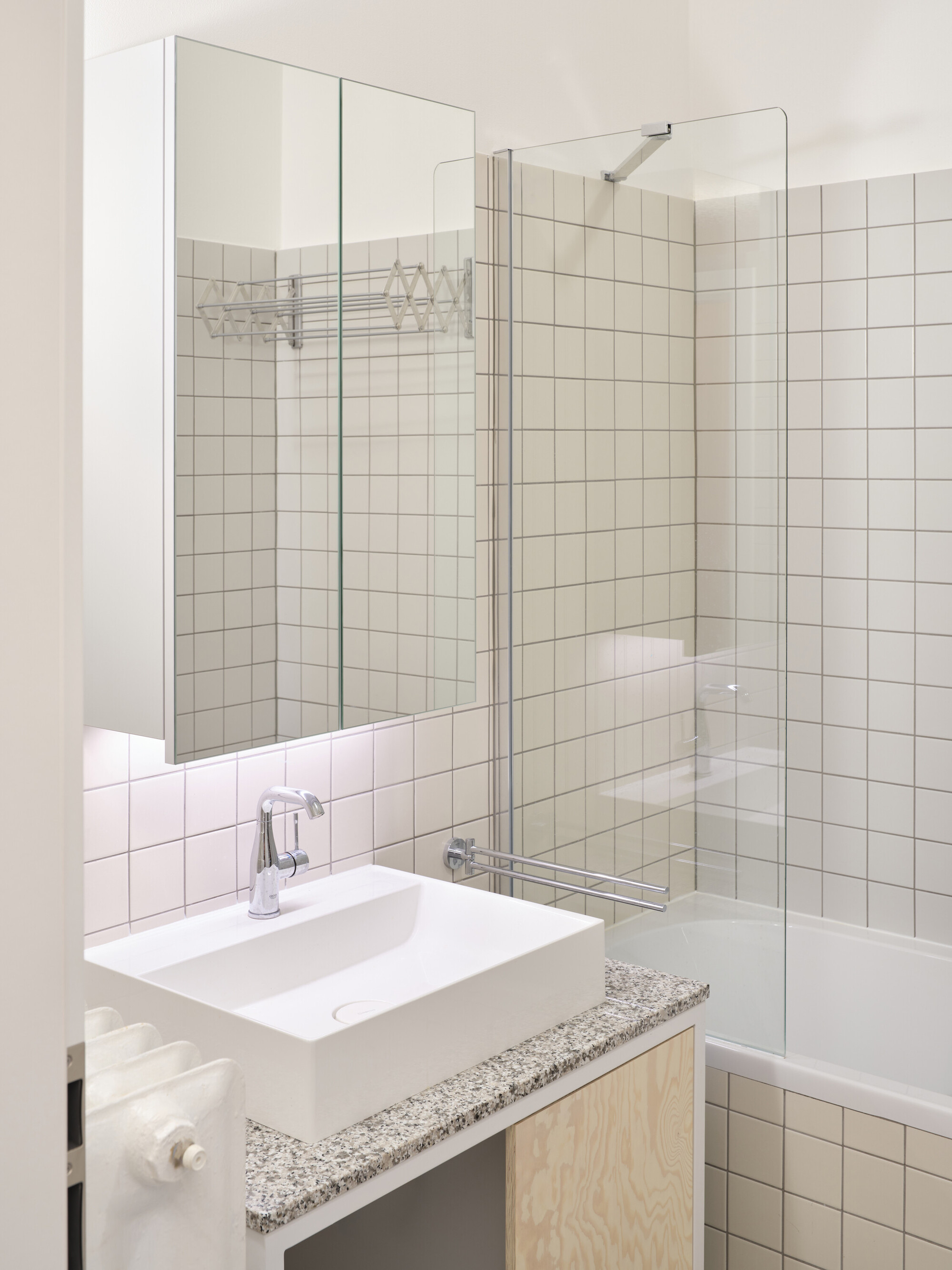 White basin on terrazzo counter with plywood cabinet and glass block partition visible at right