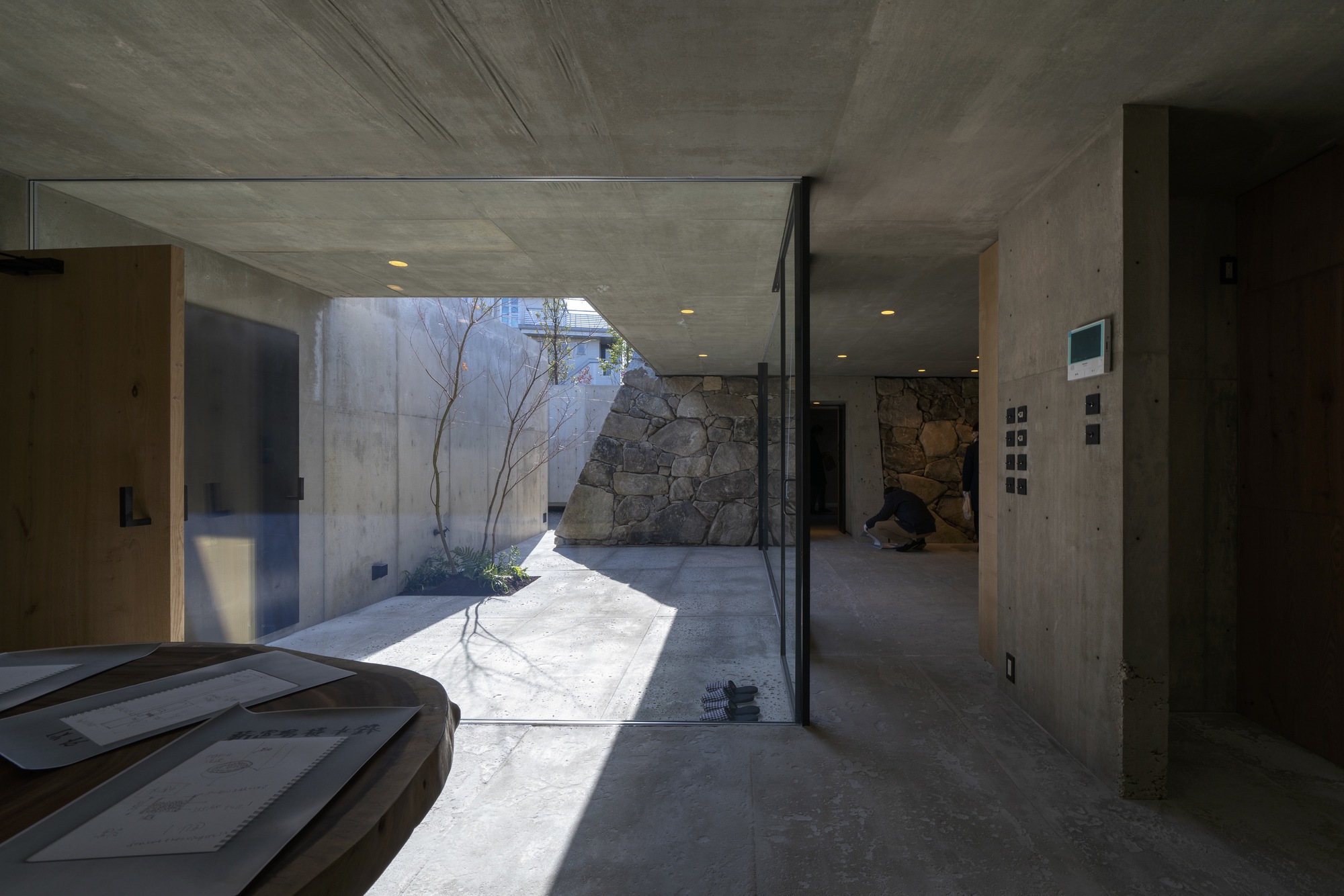 View through the interior courtyard showing concrete walls and stone feature wall in afternoon sunlight
