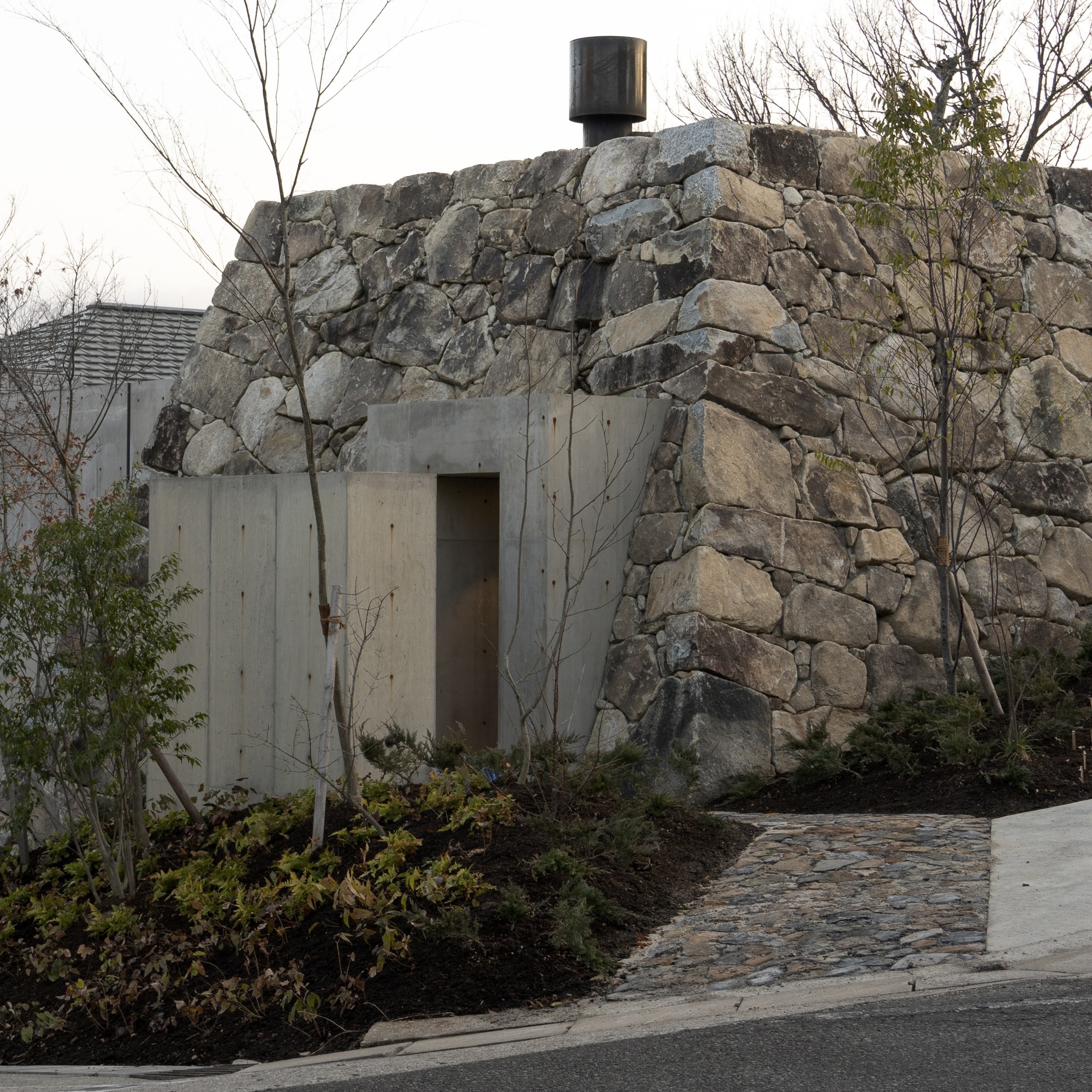 Concrete entrance portal set into a boulder face with a black chimney cap above