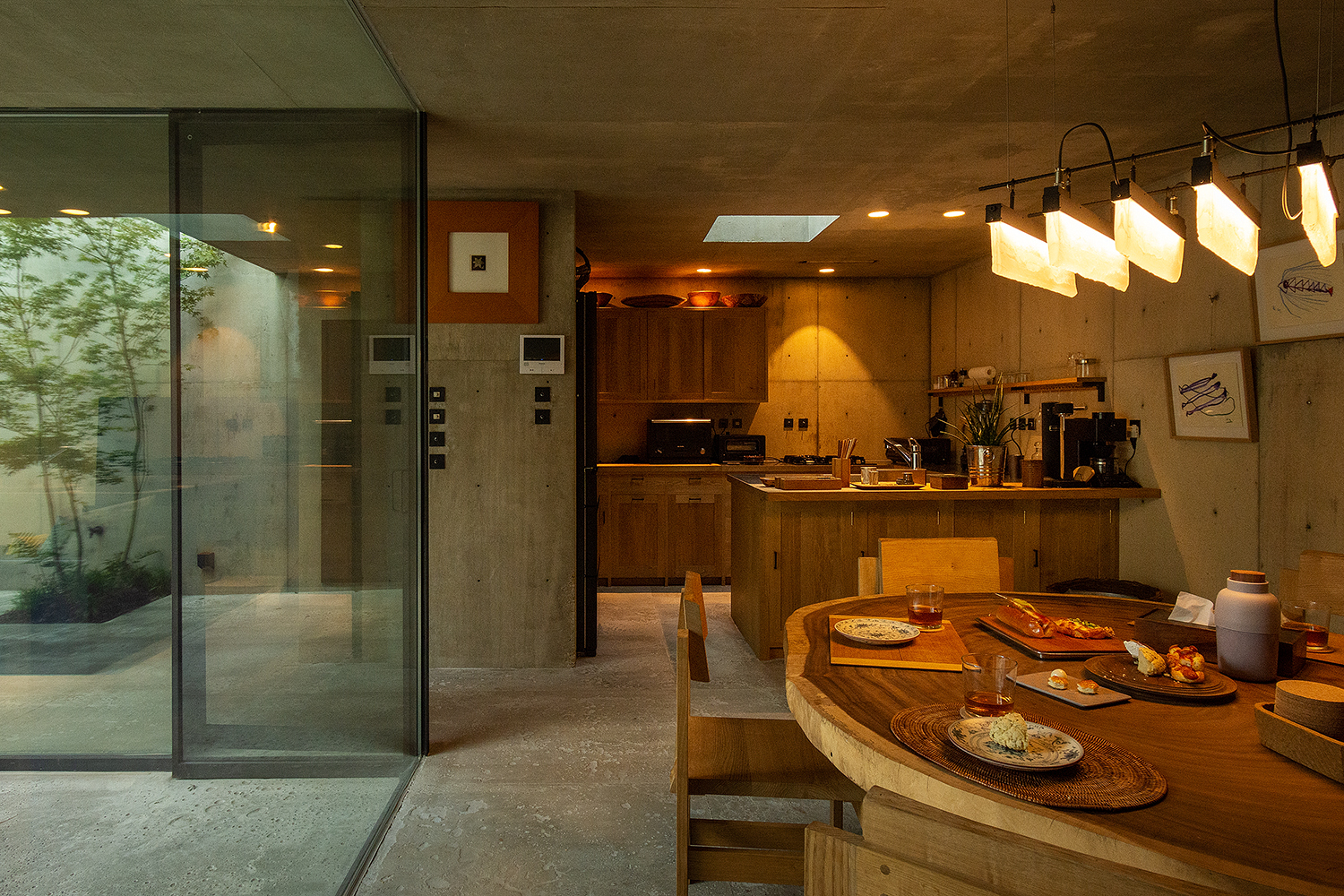 Open kitchen and dining space with timber cabinetry receiving skylight beams through the roof