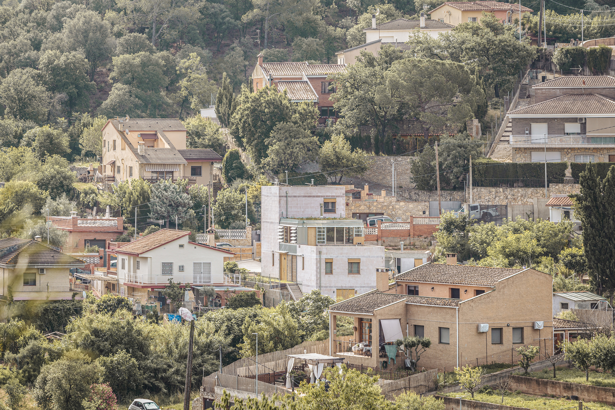 Hillside residential cluster with a timber-framed dwelling among traditional stone and stucco houses