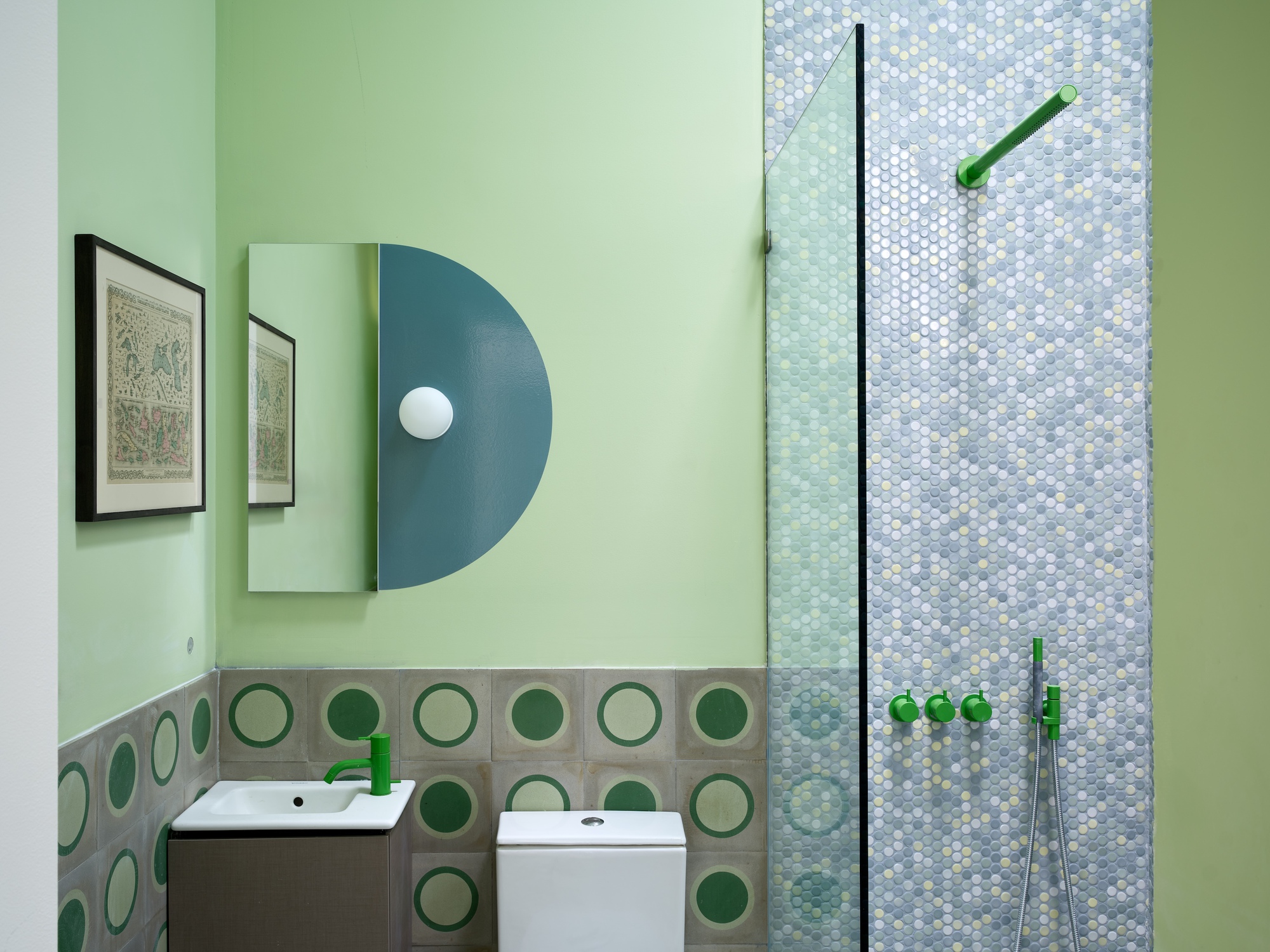 Half-circle blue-painted cabinet with round mirror above bathroom vanity and circular tile wainscot