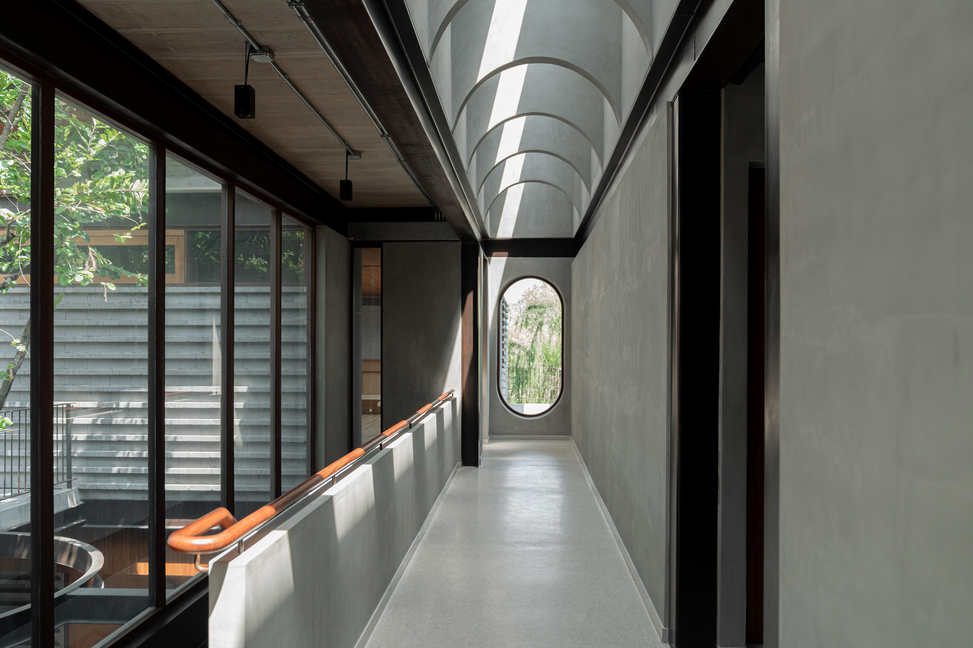 Concrete corridor with arched ceiling and oval window at the far end
