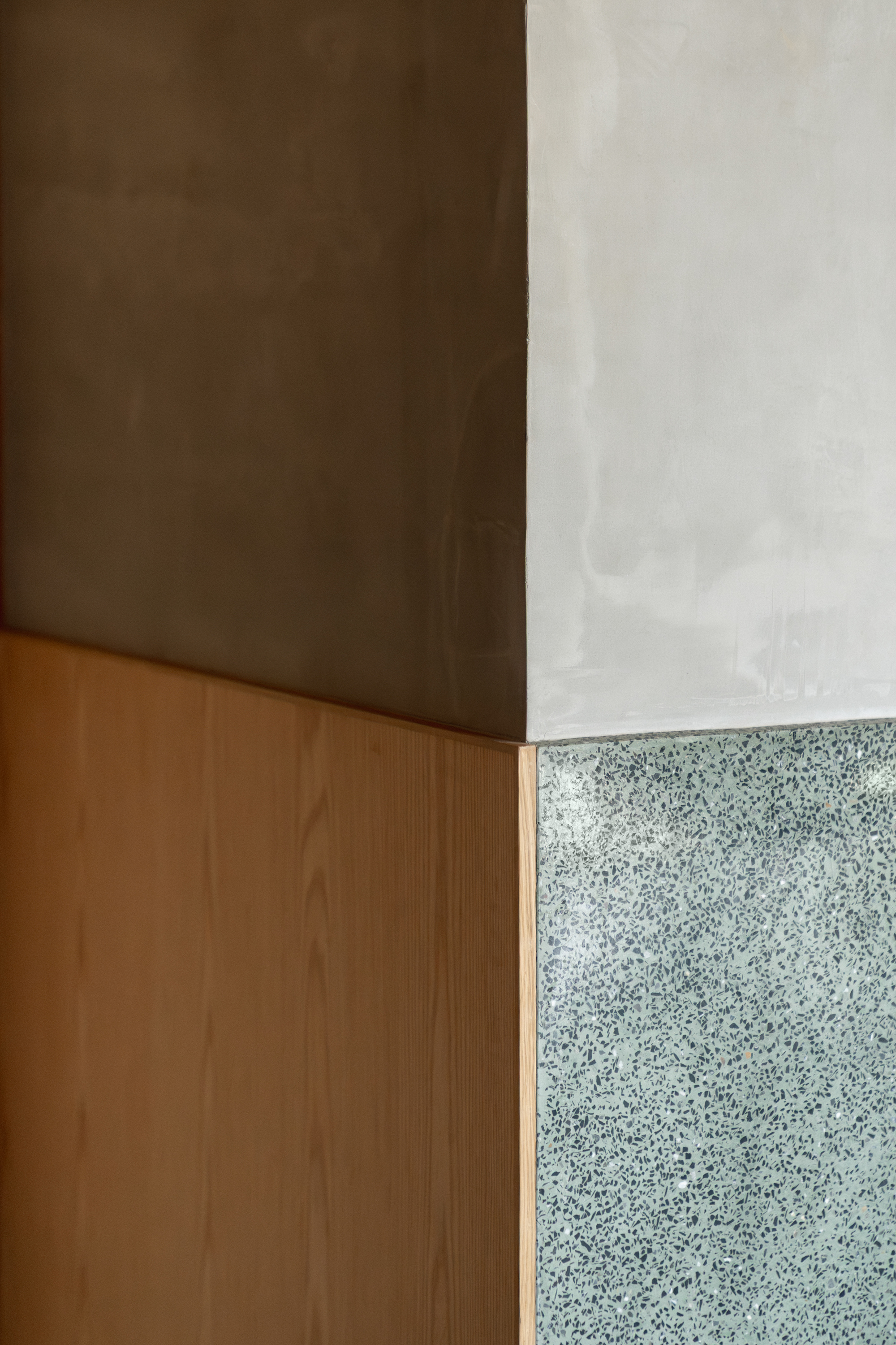 Corner detail where timber cabinetry meets polished concrete ceiling and terrazzo wall panel