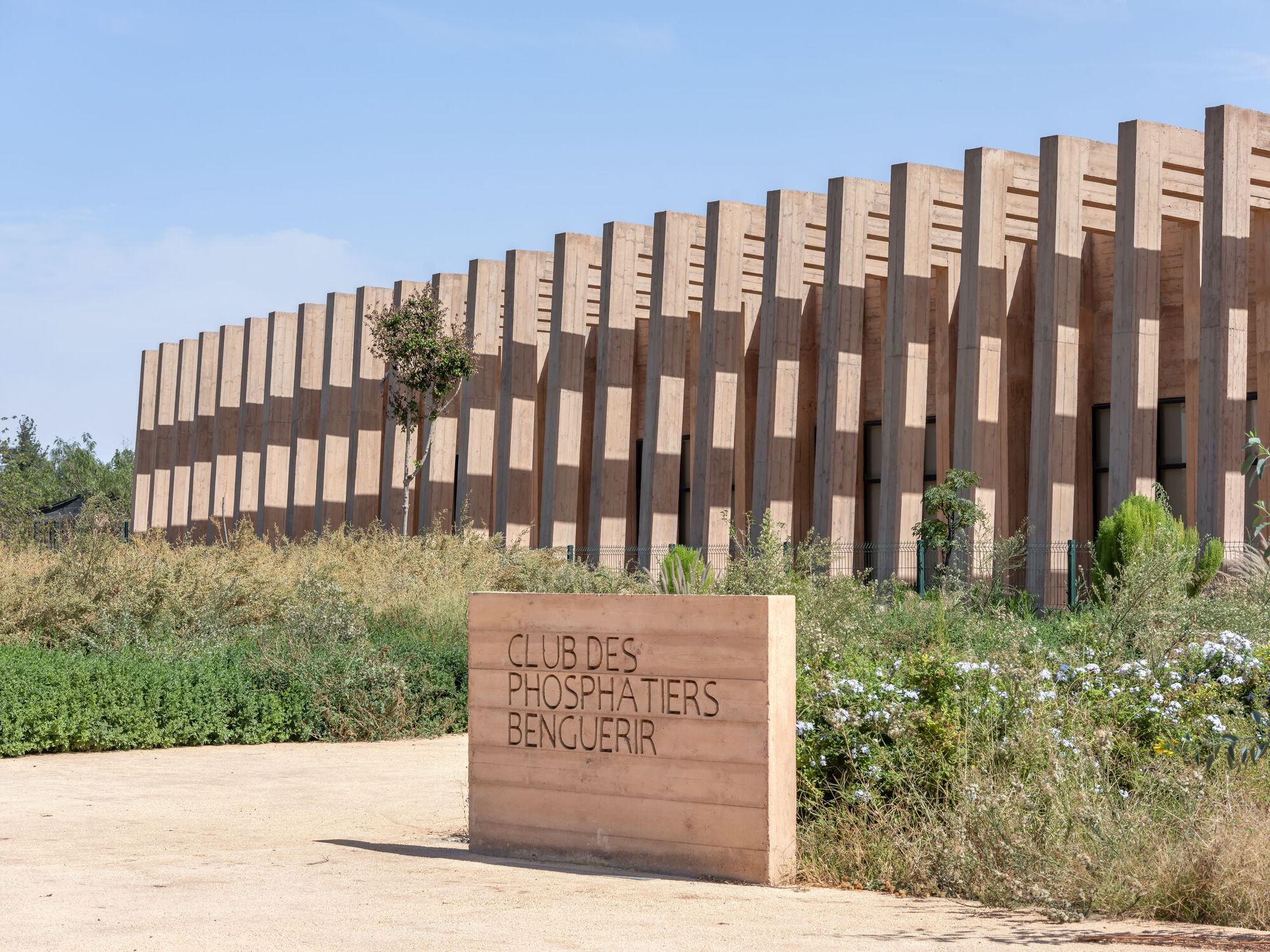 Vertical timber fin screen wrapping the facade with wildflowers and grasses in the foreground