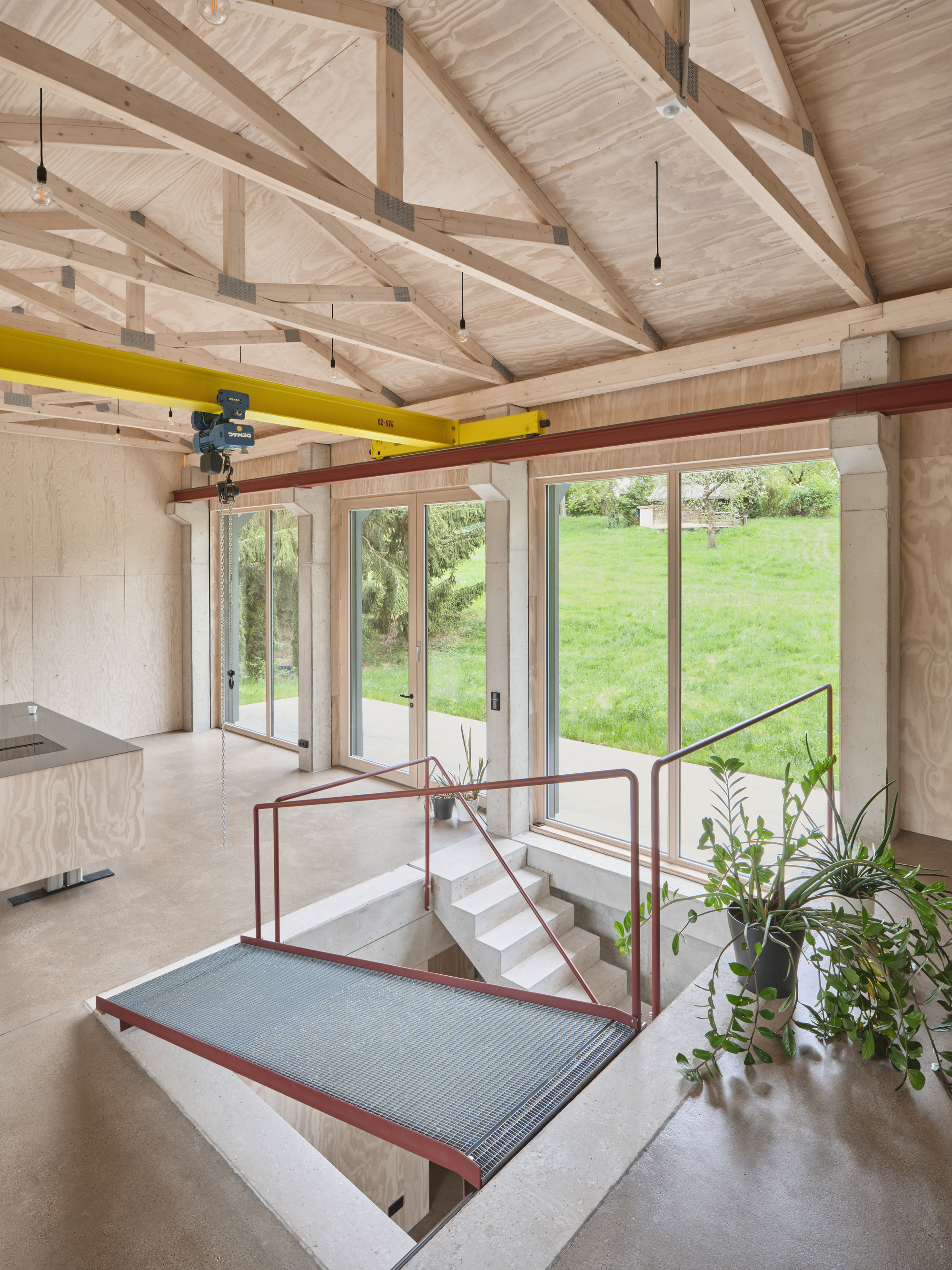 Sunken level connected by stairs with red metal railing and potted plants overlooking the sloped lawn