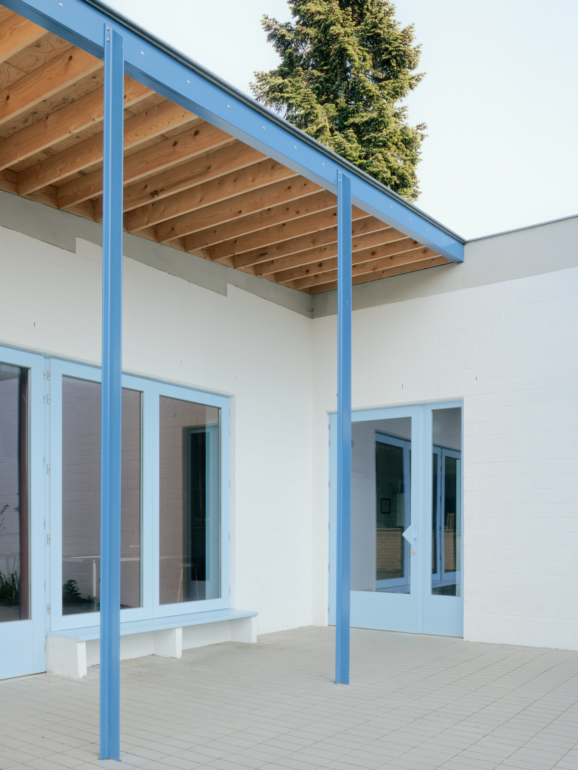 Covered patio with pale blue steel columns supporting exposed timber joists and rafters overhead