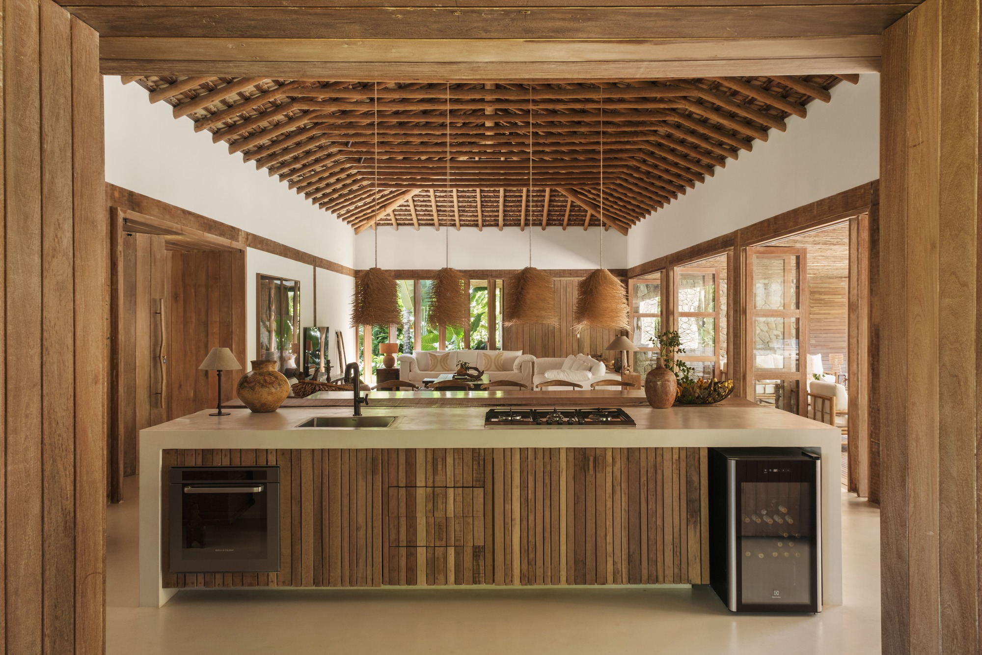 Open kitchen island beneath exposed timber roof trusses with view through to living area