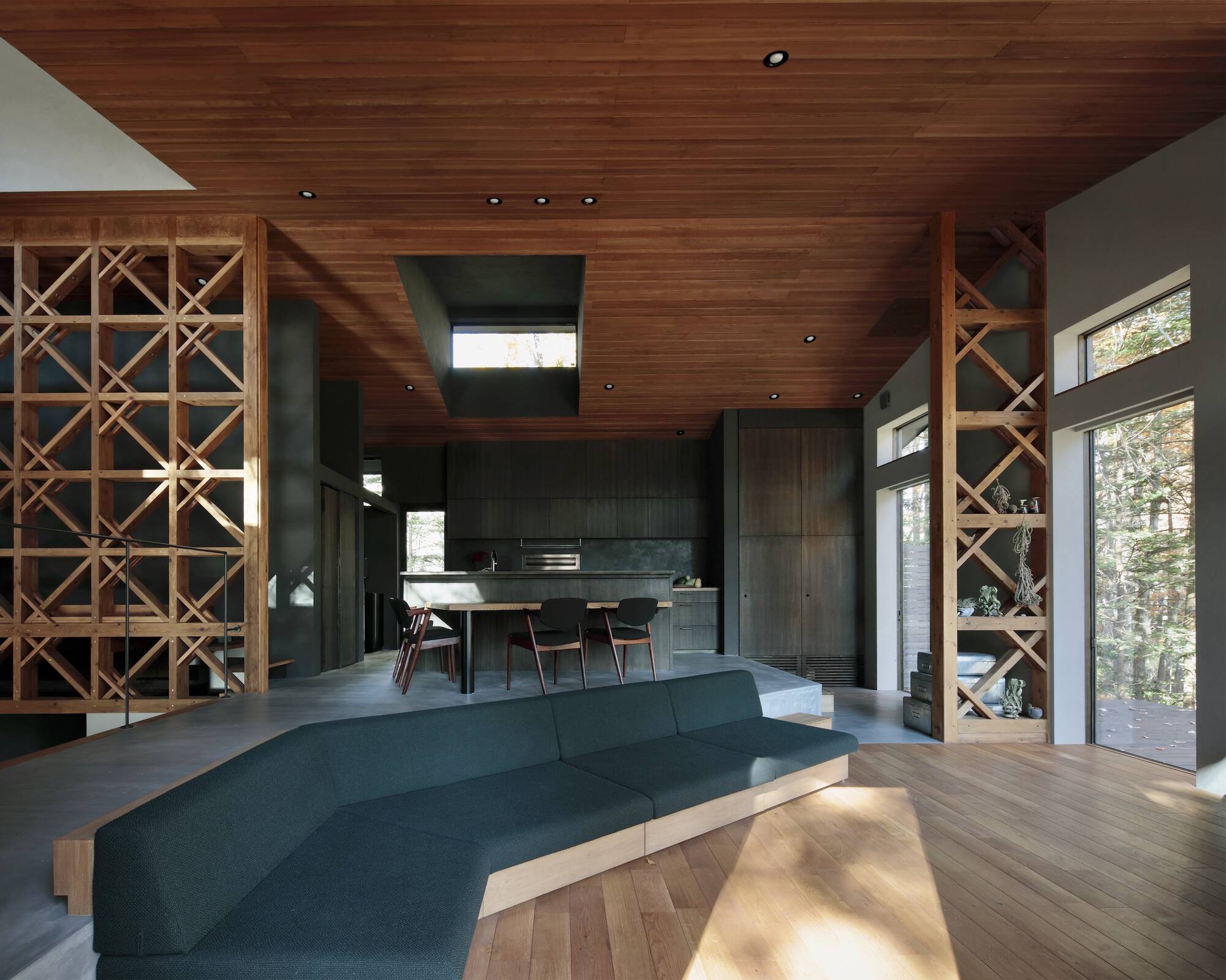 Open living area with timber lattice shelving, wood ceiling and dining zone in dappled afternoon light