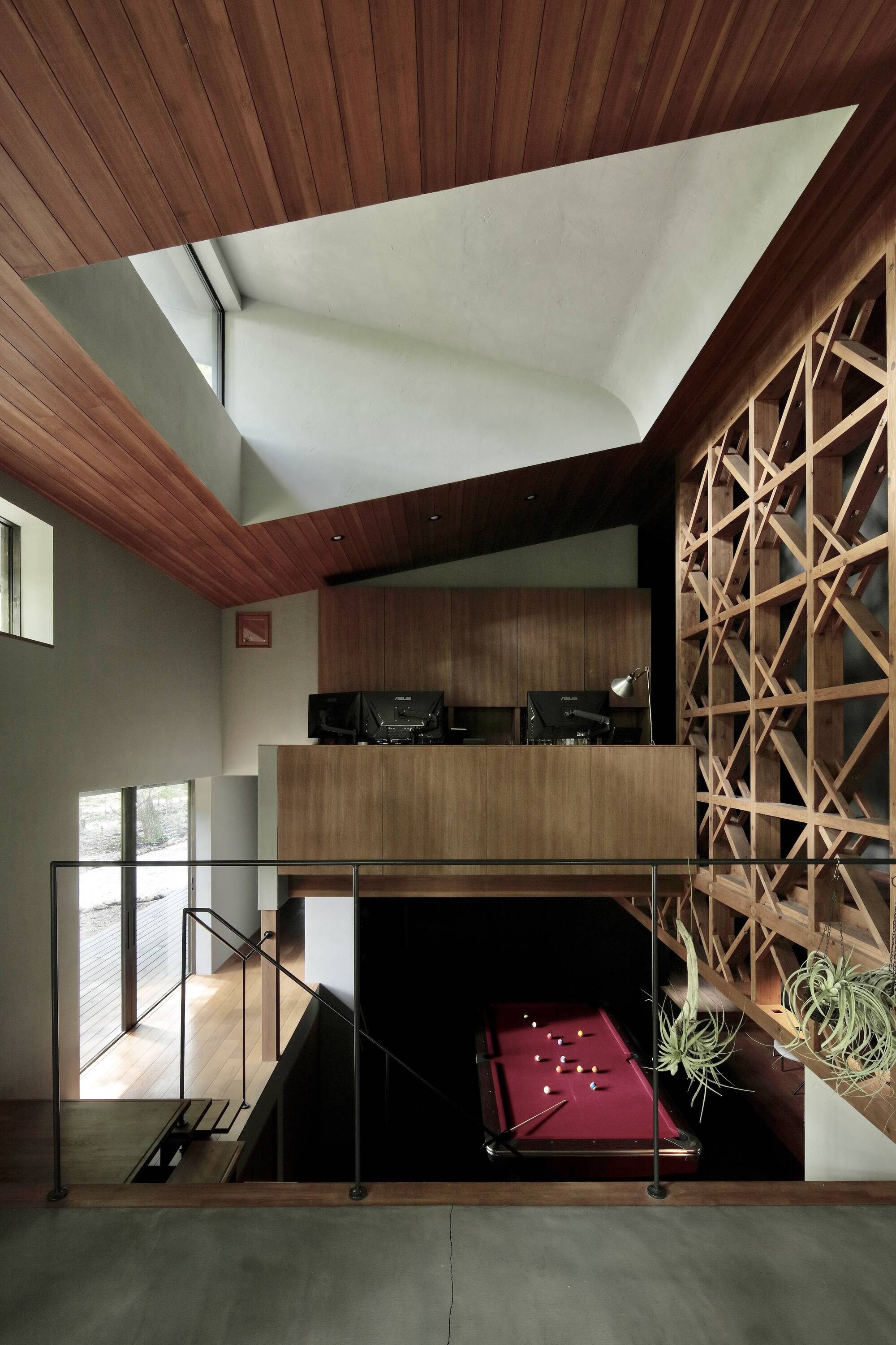 View from upper level down to billiard table with pyramidal skylight and timber lattice wall