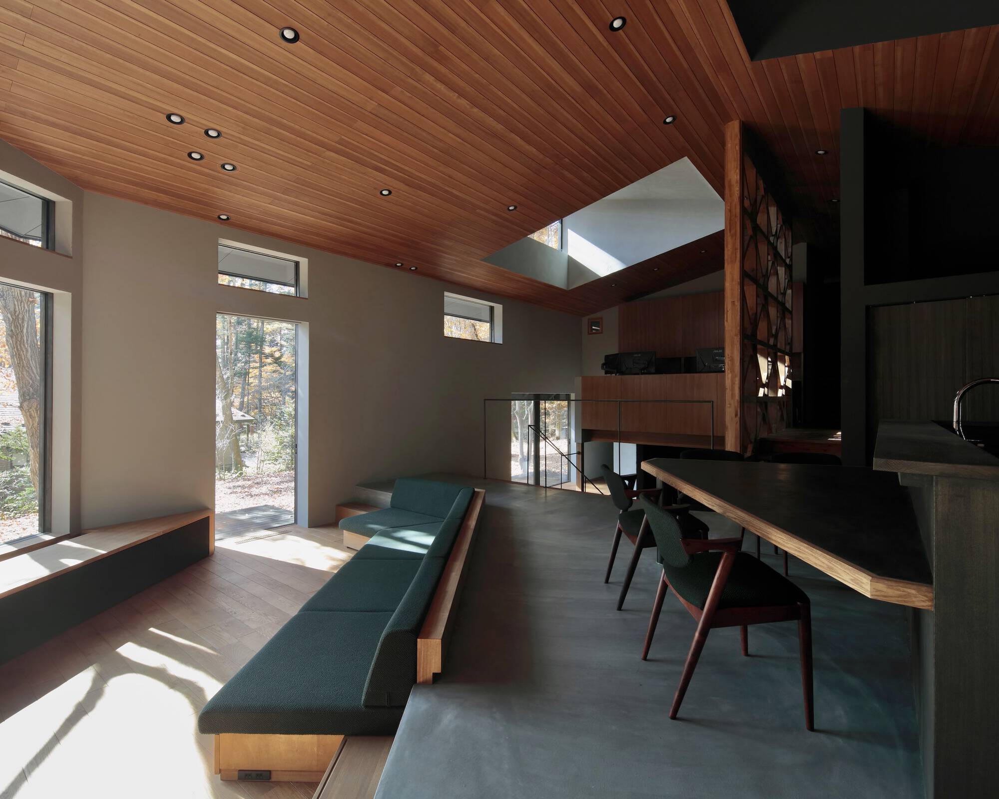 Open living and dining area with angled wood ceiling and sunlight filtering through windows