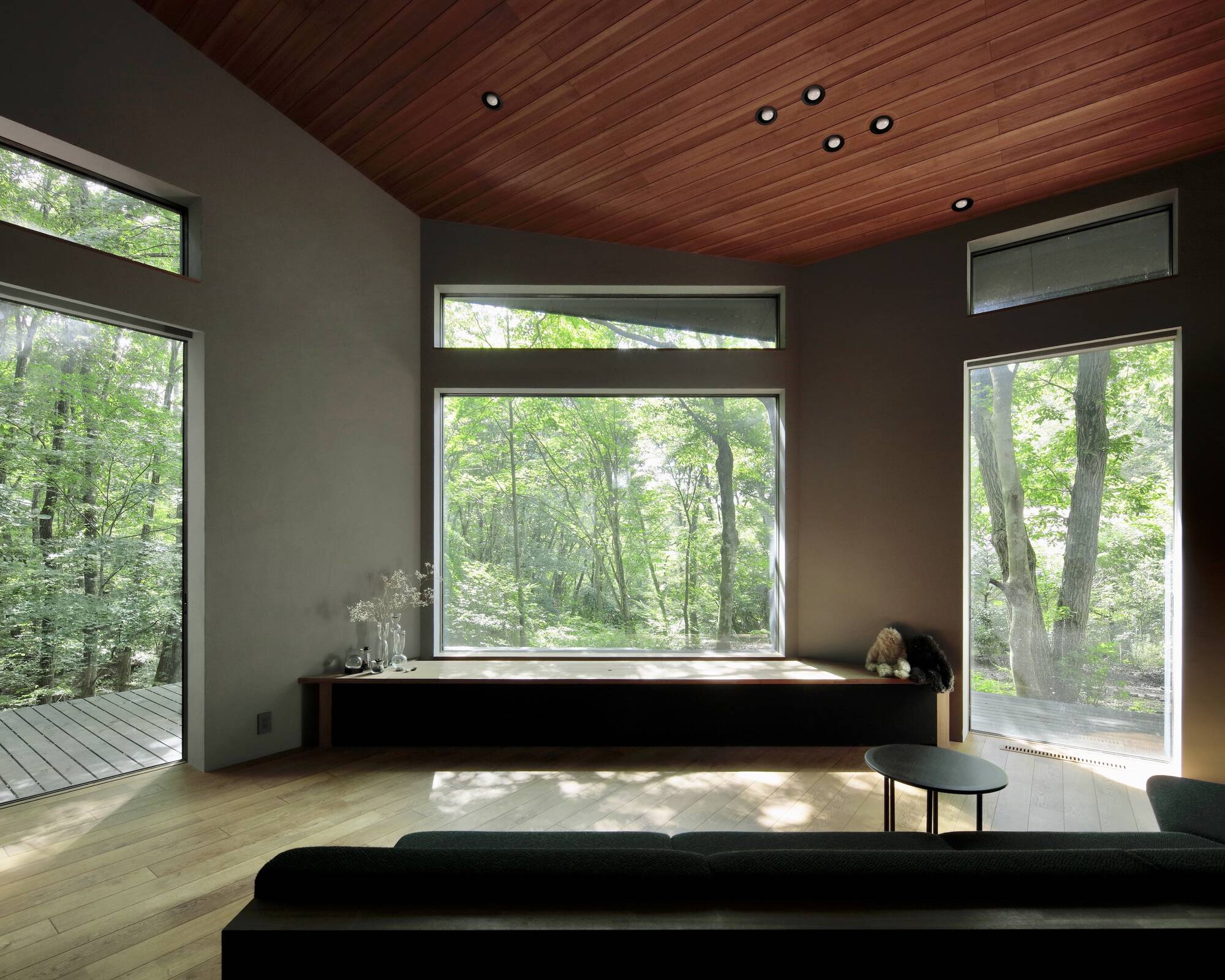 Corner window seat framed by wood ceiling and views of surrounding trees
