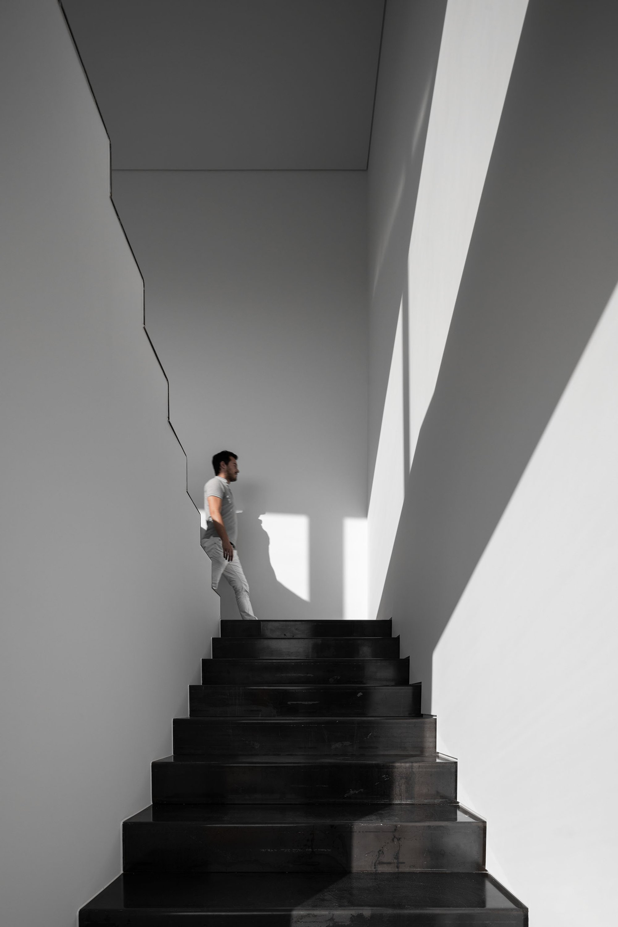 Sculptural stairwell carved in light and shadow, defining a minimalist spatial experience.