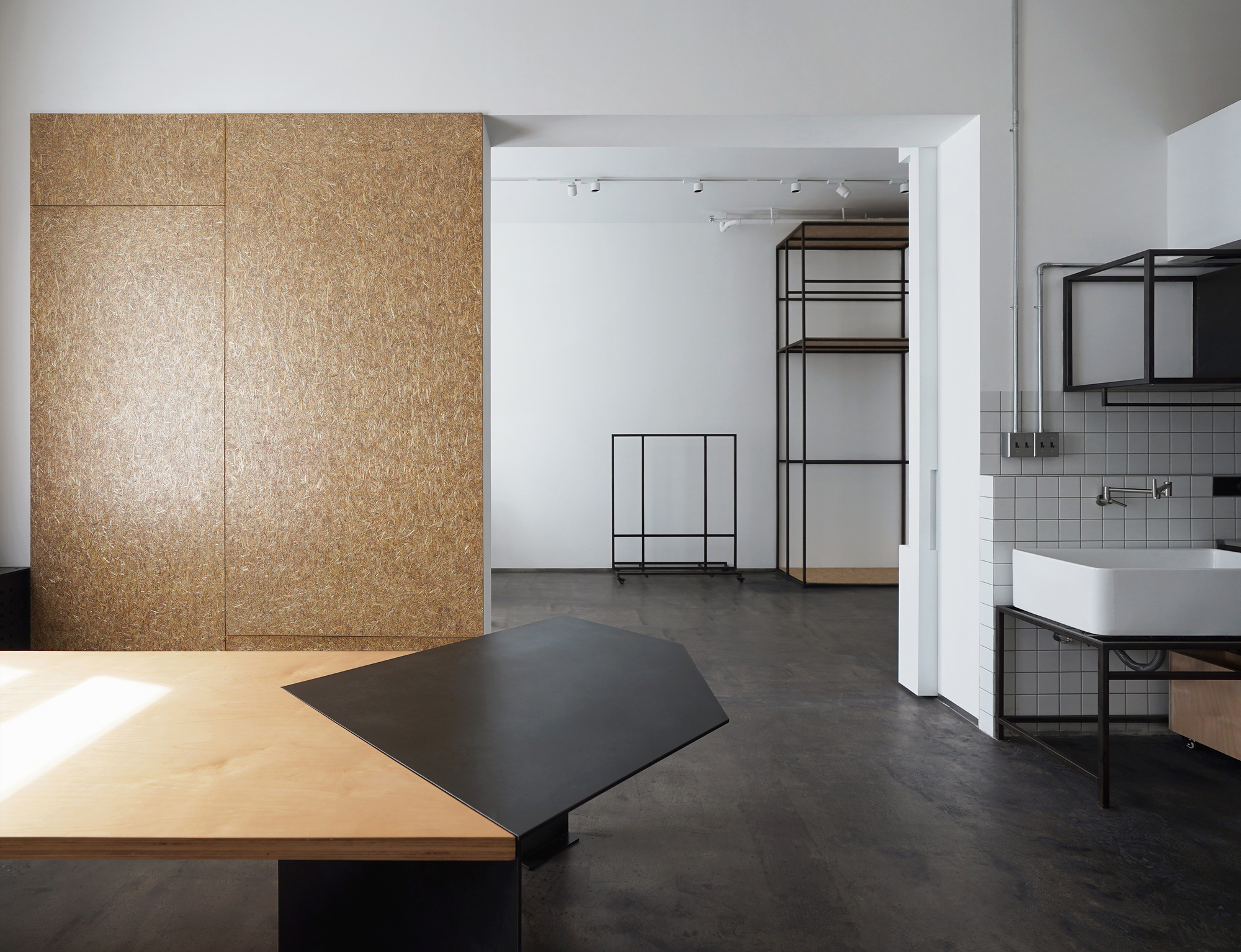 View through white doorway to open-frame metal shelving unit and sink beyond polished concrete floor