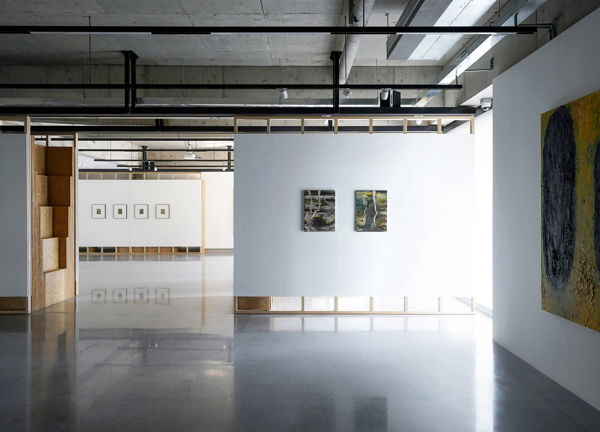 Polished concrete floor reflecting cork partitions and white walls hung with framed photographs