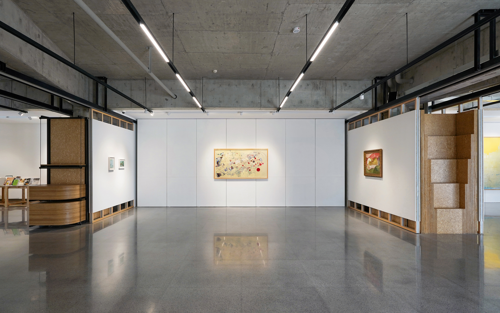 Exhibition hall with modular white wall system and polished concrete floor reflecting overhead lighting