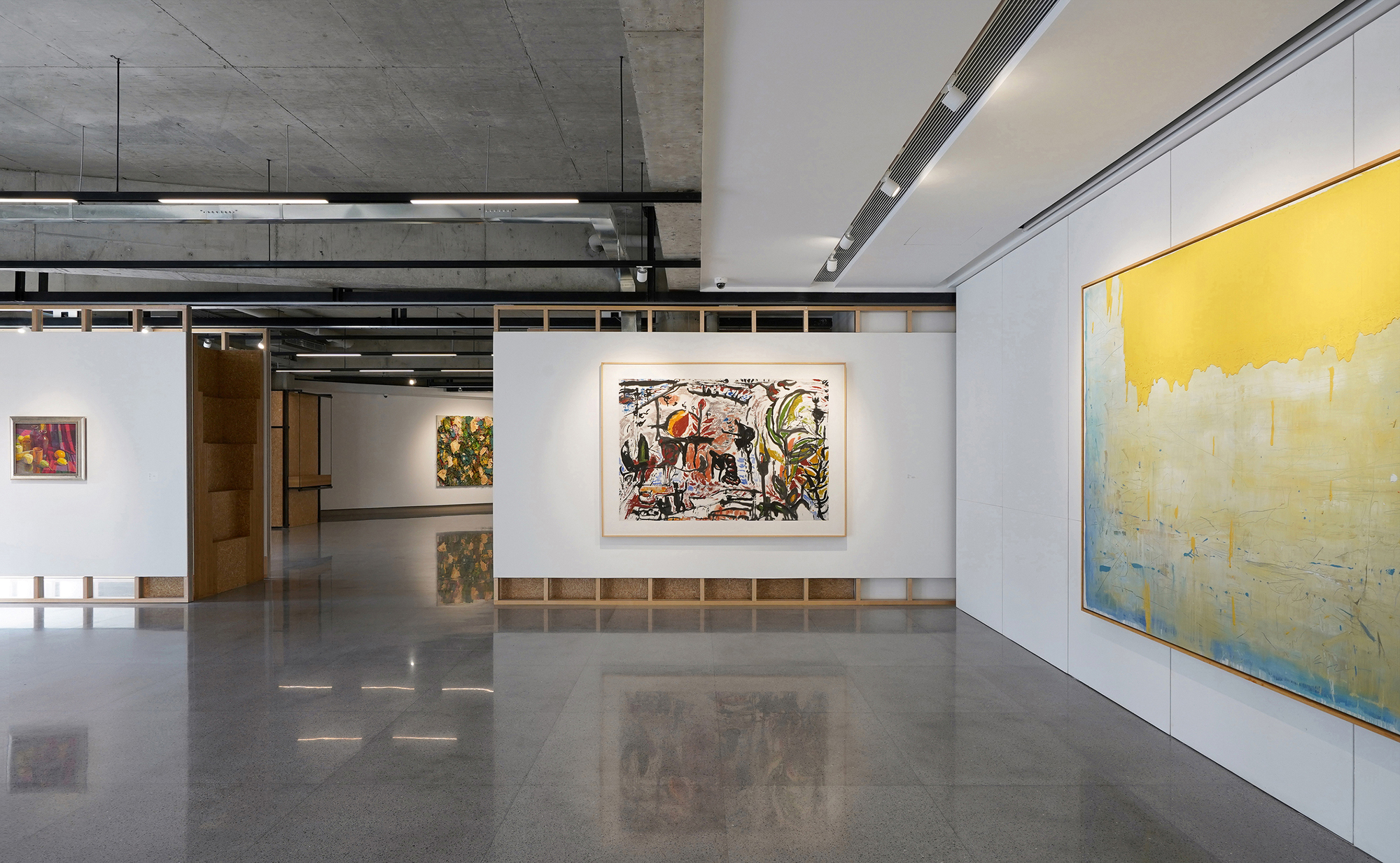 Gallery interior with reconfigurable partition walls displaying artworks under linear suspended light fixtures