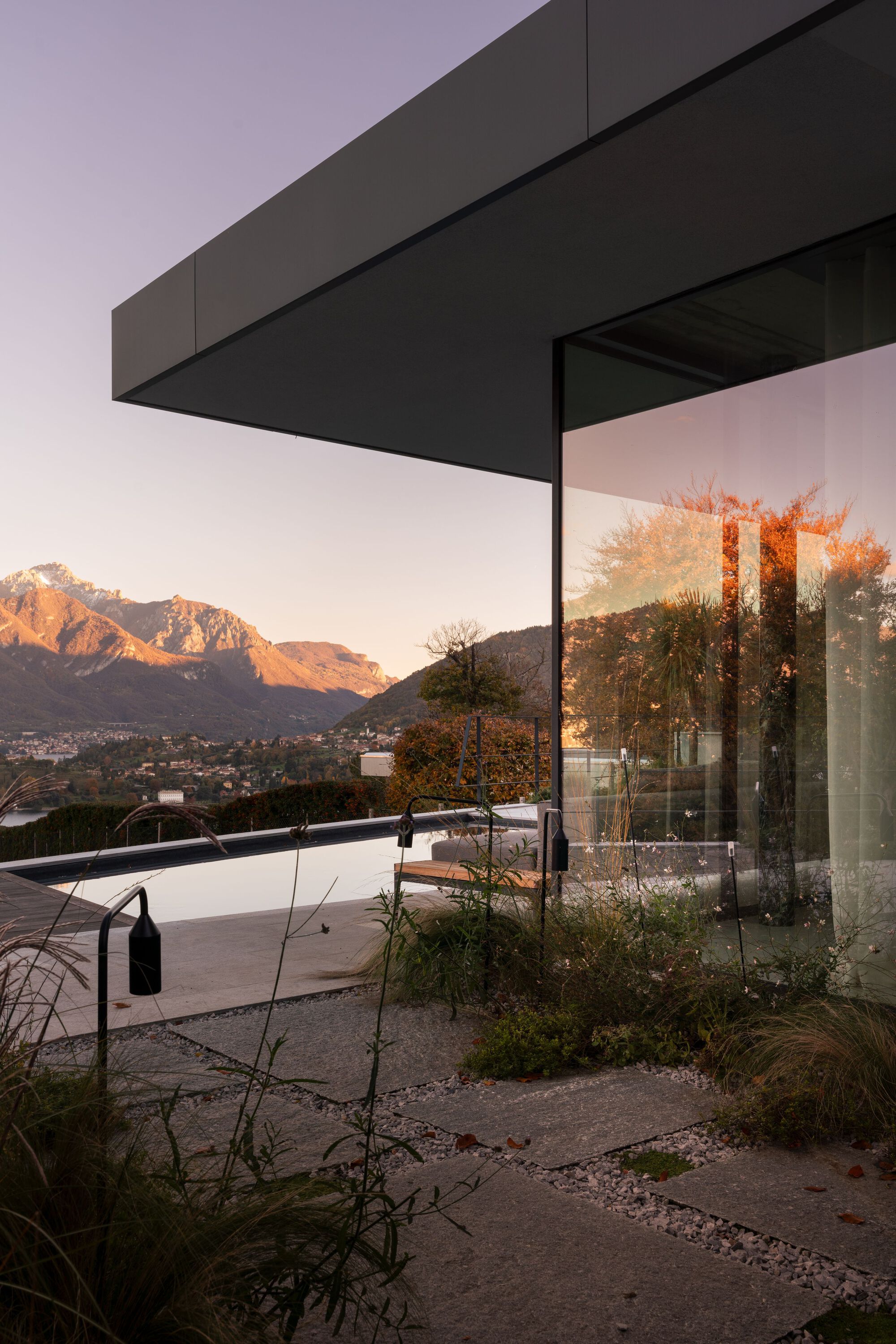 Cantilevered roof overhang above planted courtyard with mountains visible at sunset