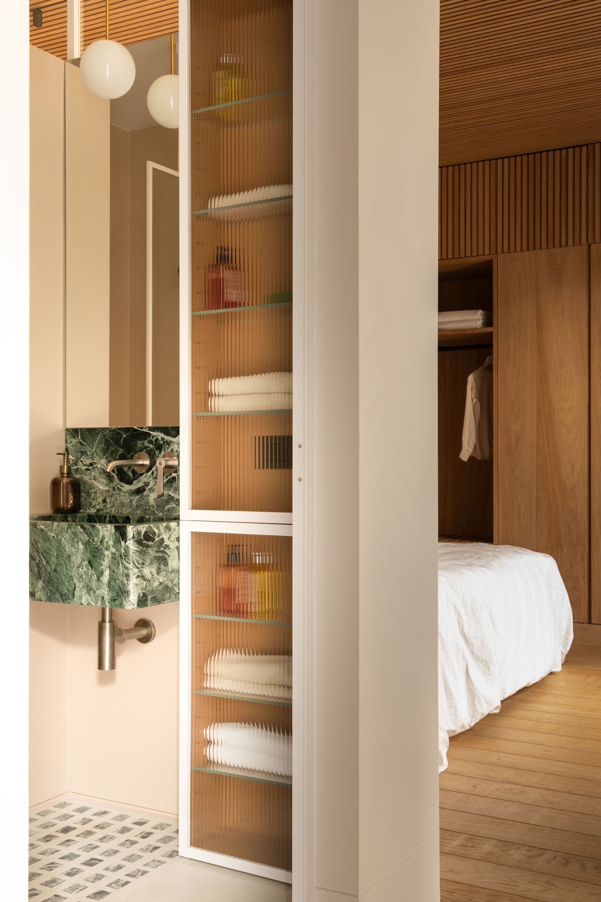 Ensuite passage with green marble vanity, fluted glass cabinet, and view through to bedroom wardrobe