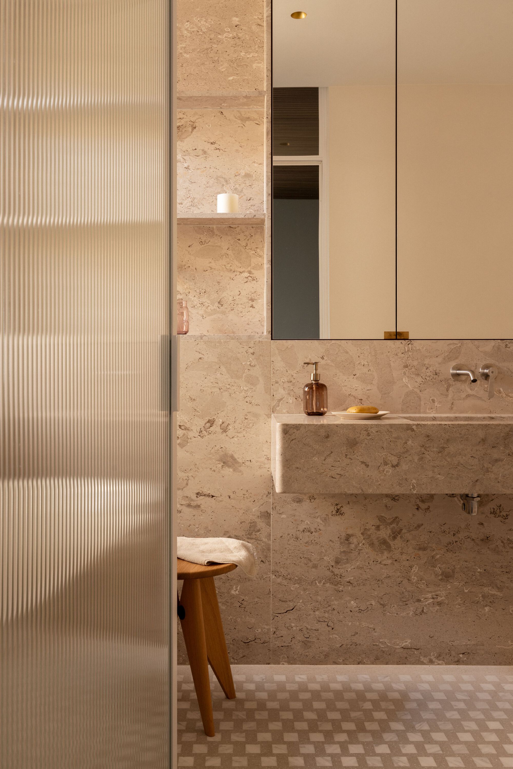 Bathroom with travertine walls, floating vanity and fluted glass partition panel