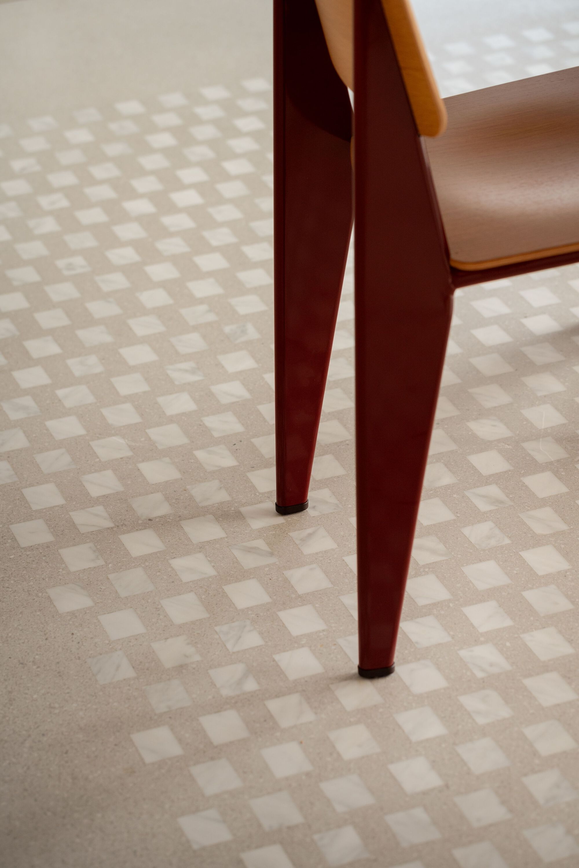 Tapered timber chair legs on chequered terrazzo floor tiles