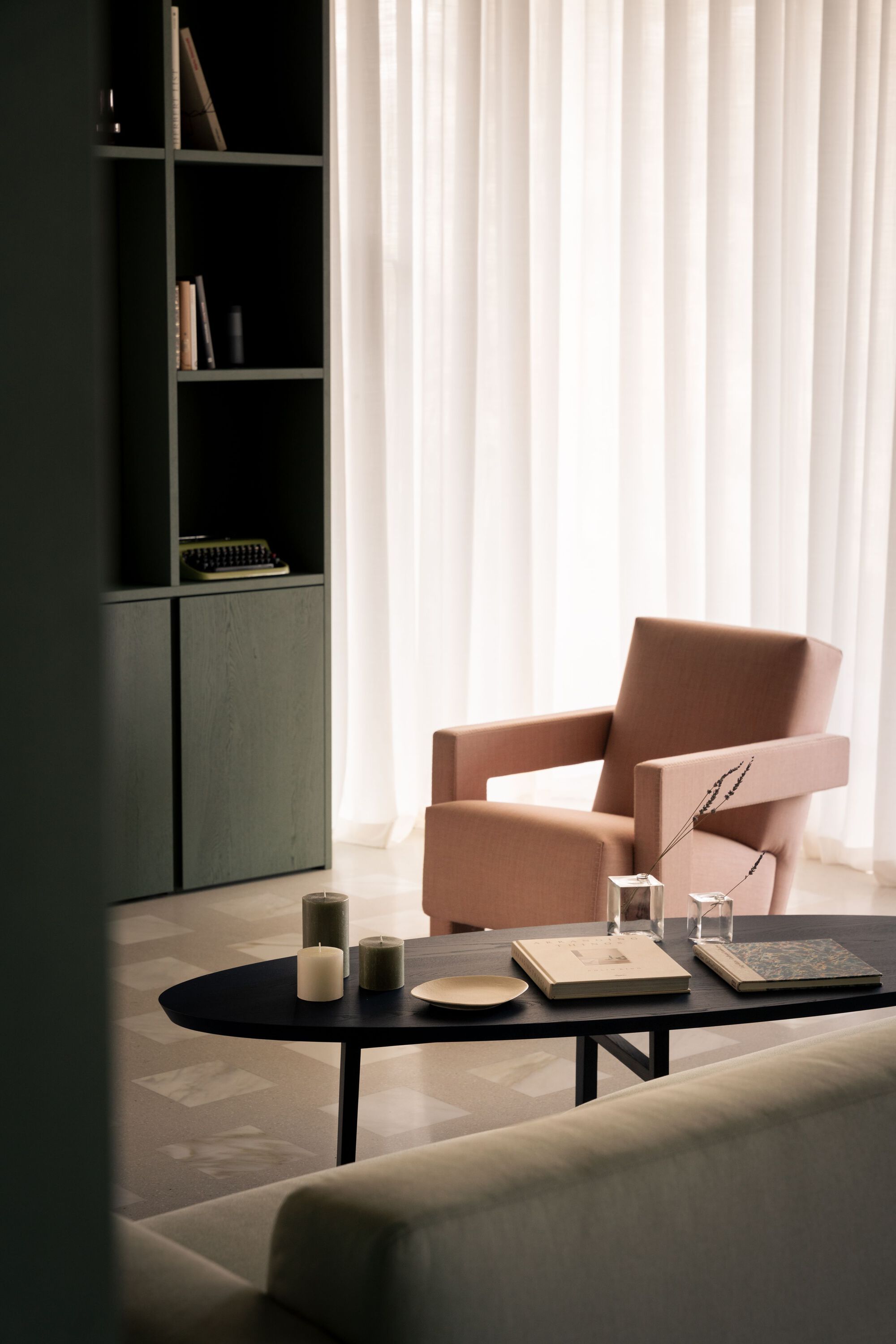 Living room with a terracotta armchair, black coffee table and floor-to-ceiling curtains in daylight
