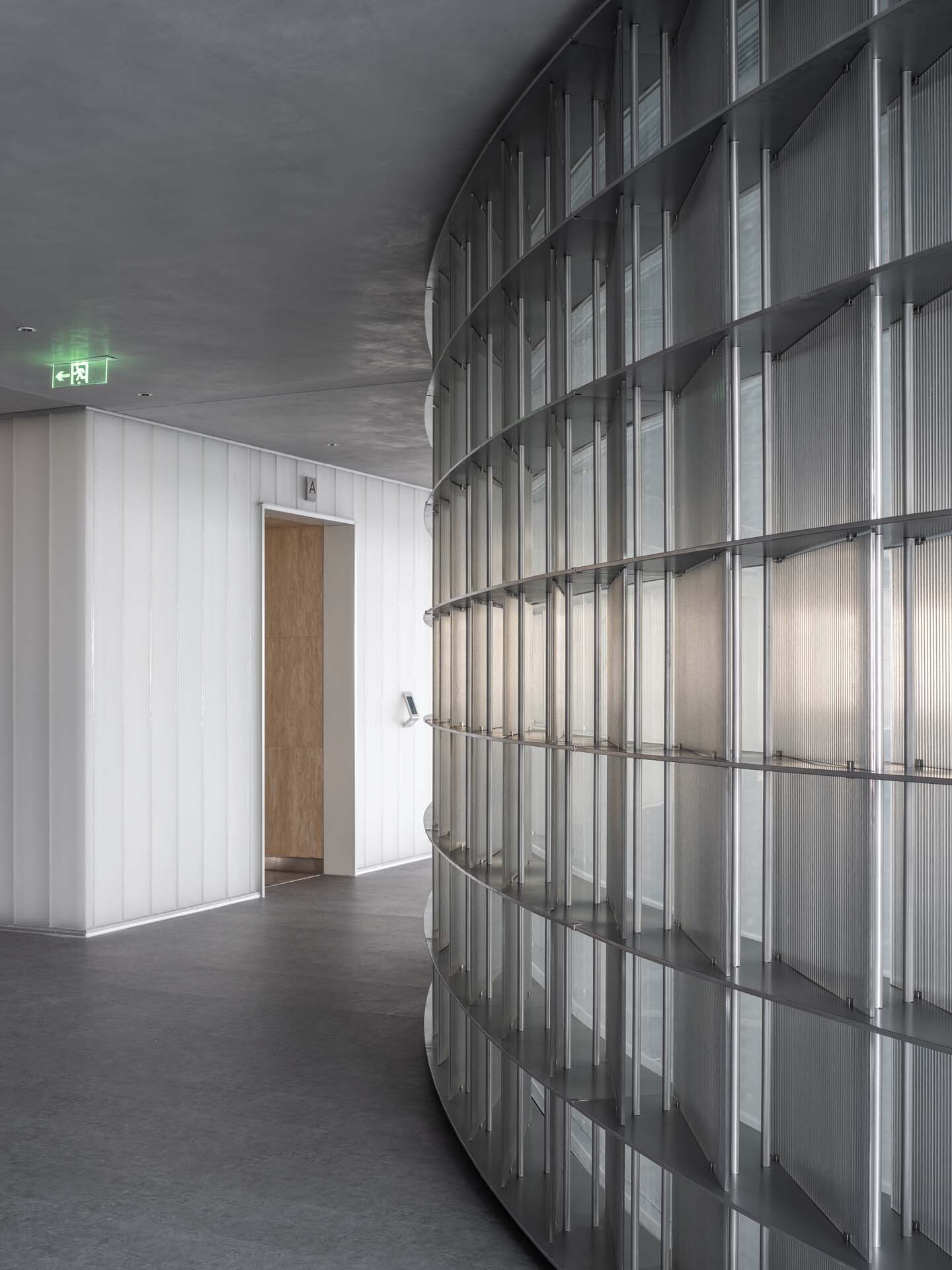 Curved translucent glass block wall adjacent to vertical ribbed panel and single wooden door