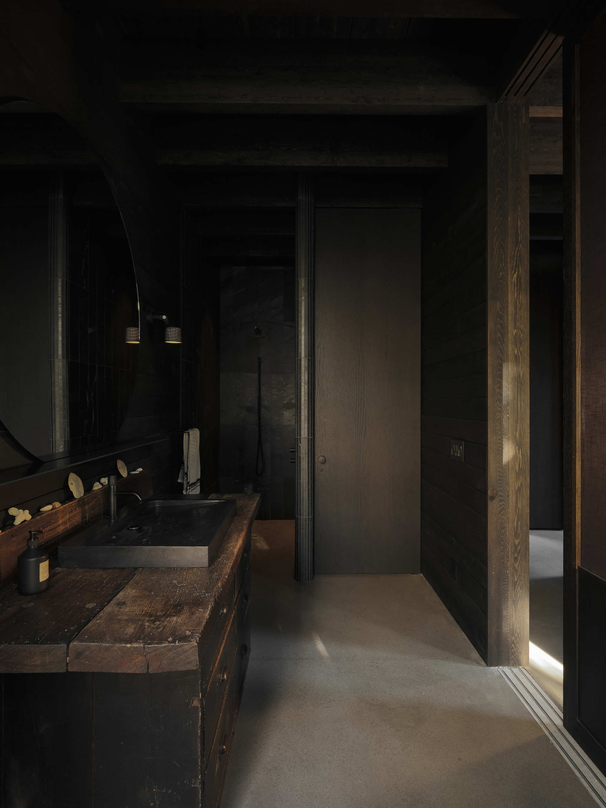 Narrow bathroom corridor with reclaimed wood vanity and vertical strip of natural light at edge