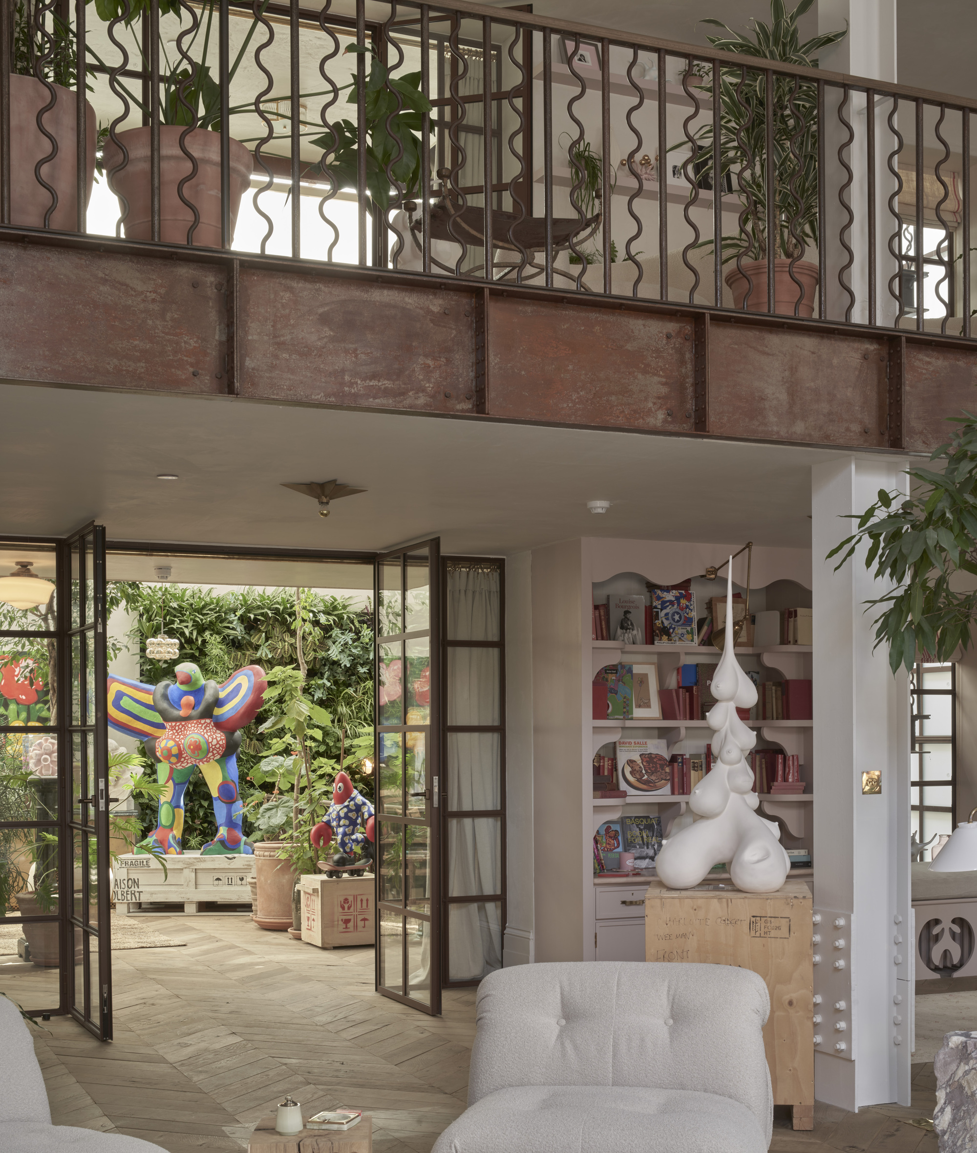 Steel-framed folding doors opening to a planted courtyard with decorative metal railing above